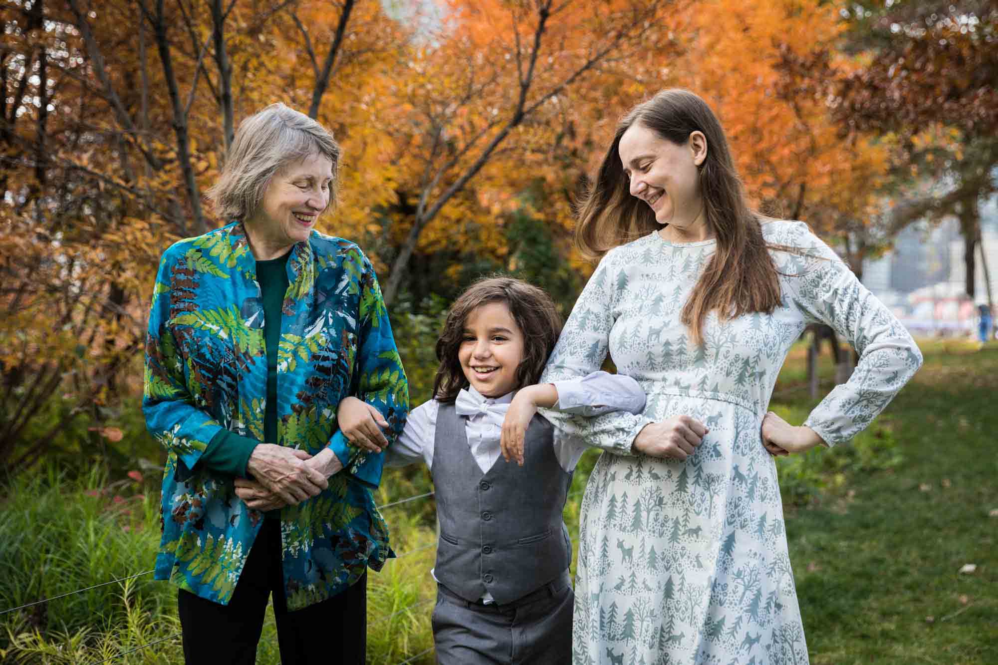 Mother and grandmother walking arm-in-arm with young boy in Brooklyn Bridge Park