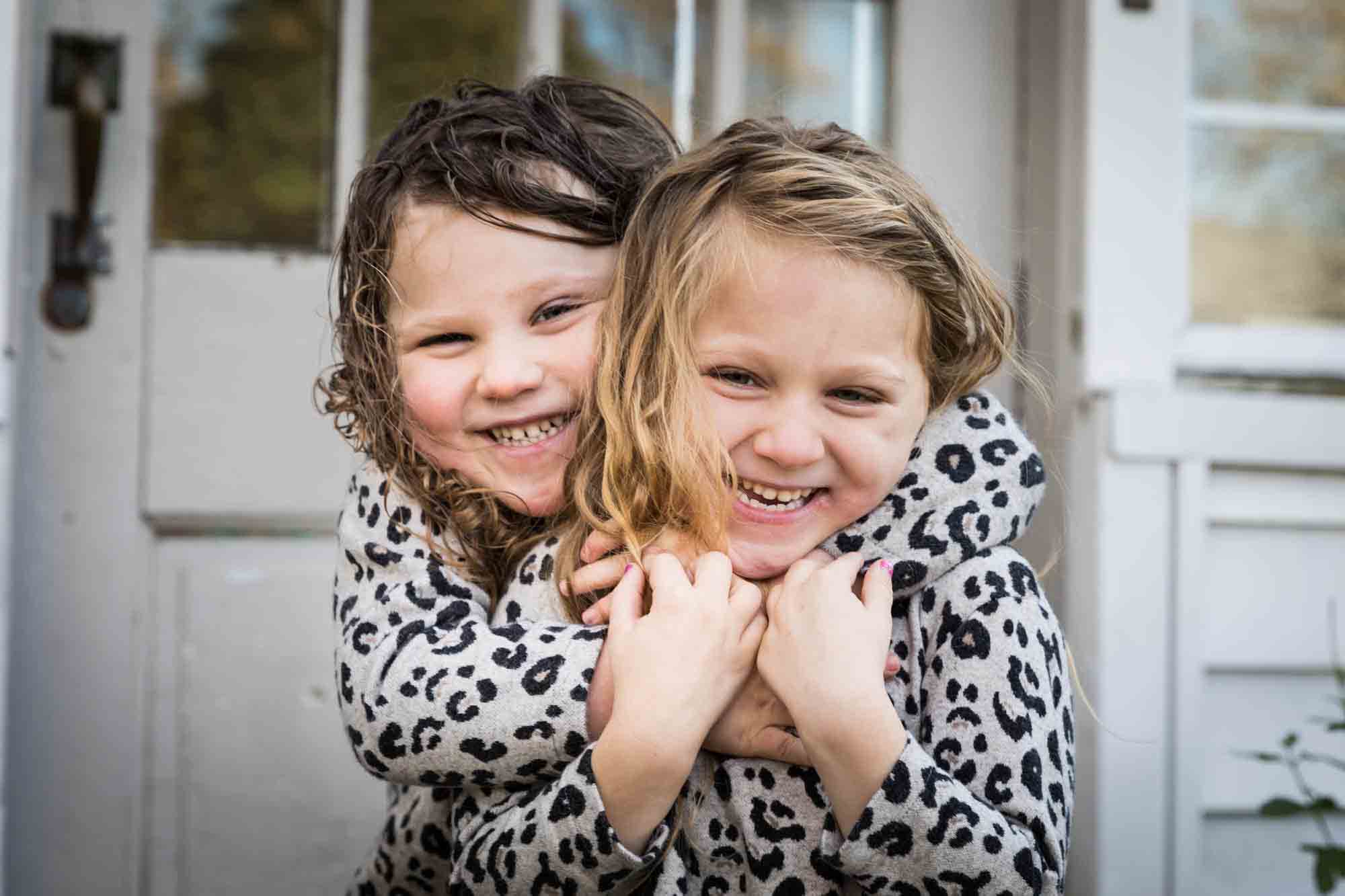Two little girls hugging each other for an article advertising family portrait gift certificates