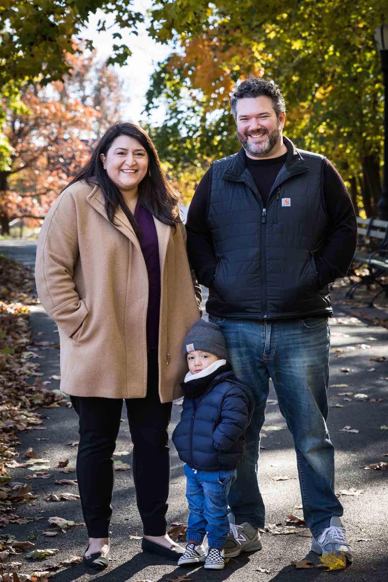 Parents and little boy posing for photo with hands in pockets