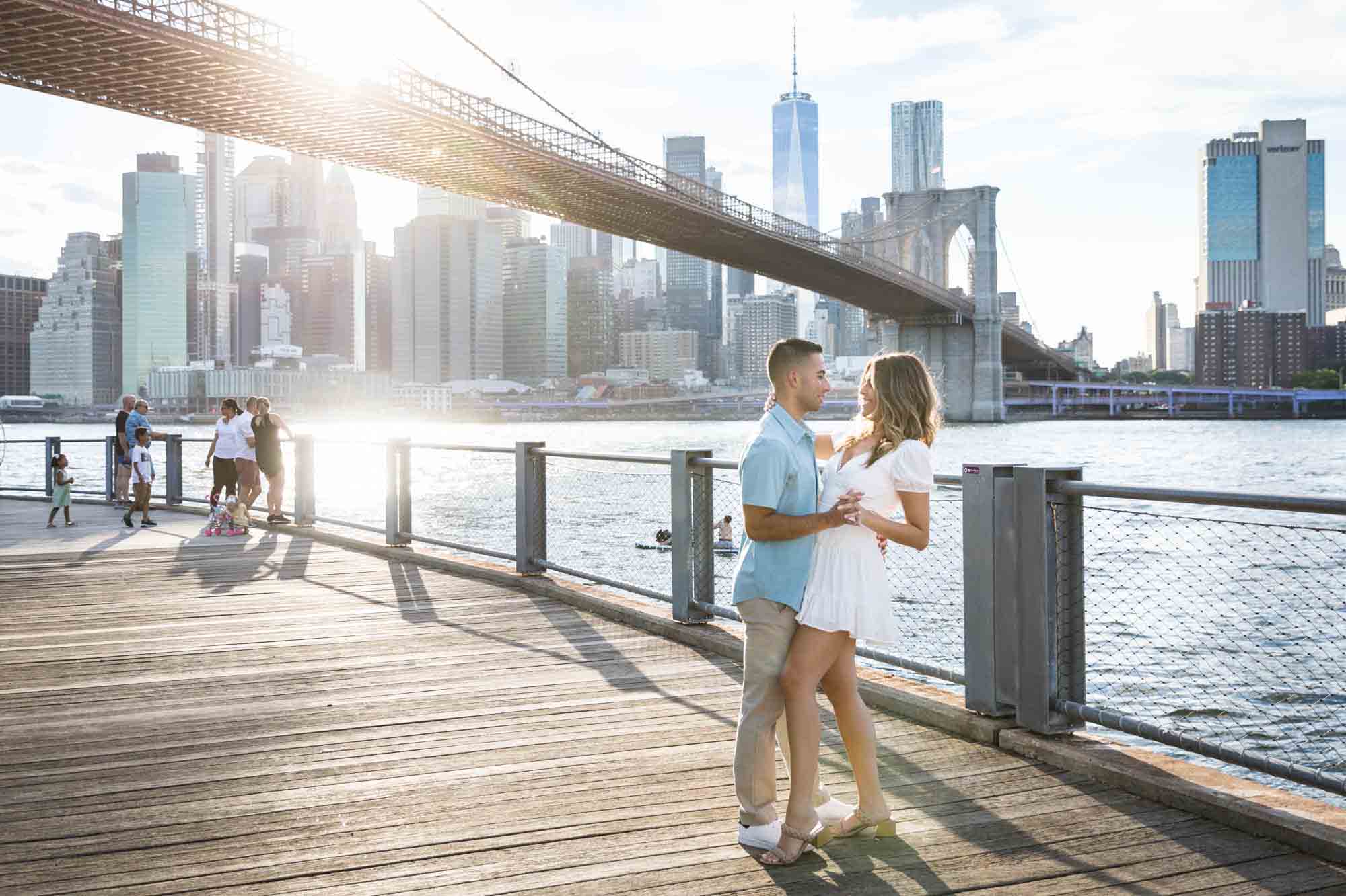 Couple dancing on boardwalk in front of Brooklyn Bridge during a surprise proposal in Brooklyn Bridge Park