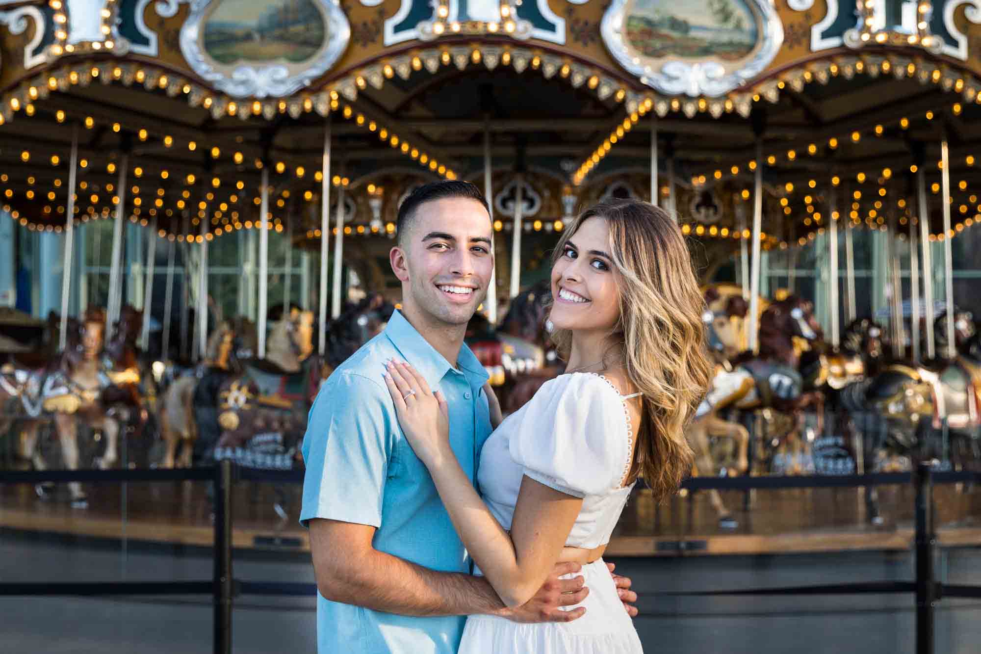 Couple smiling in front of Jane's Carousel for an article on how to propose in Brooklyn Bridge Park