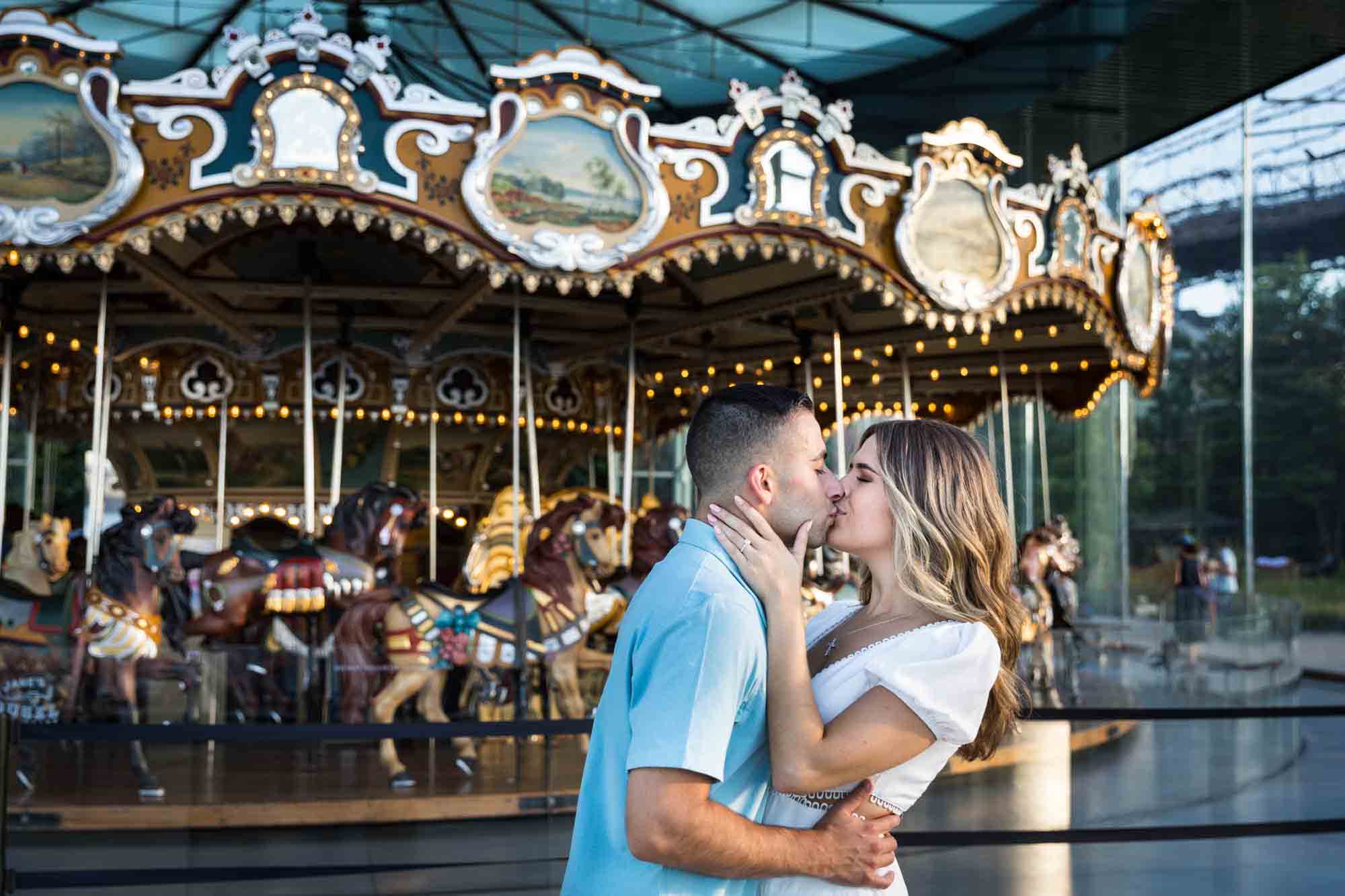 Couple kissing in front of Jane's Carousel in Brooklyn Bridge Park