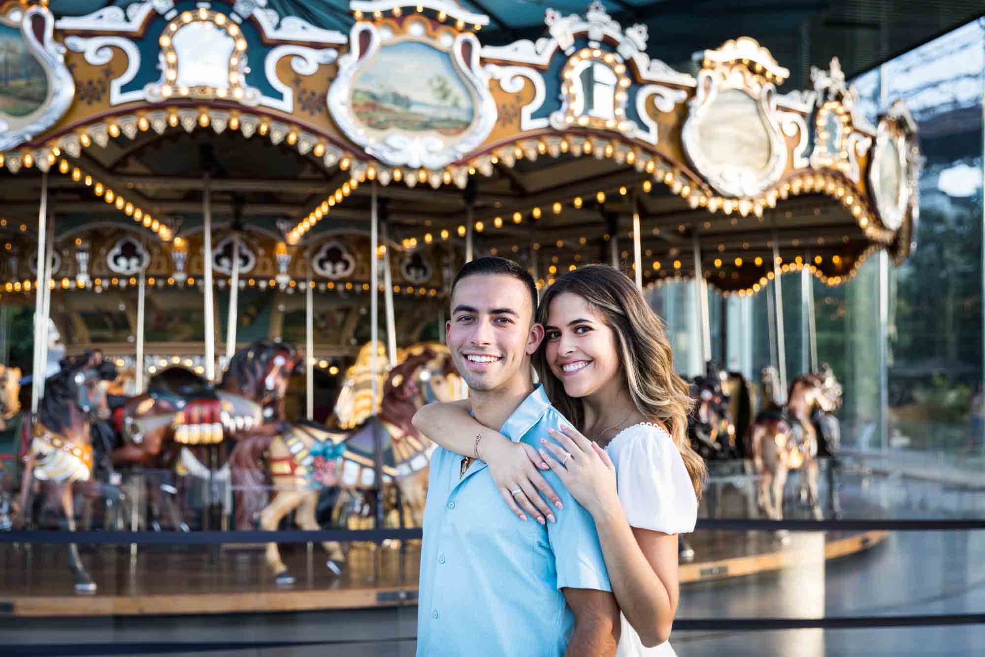 Couple hugging in front of Jane's Carousel in Brooklyn Bridge Park