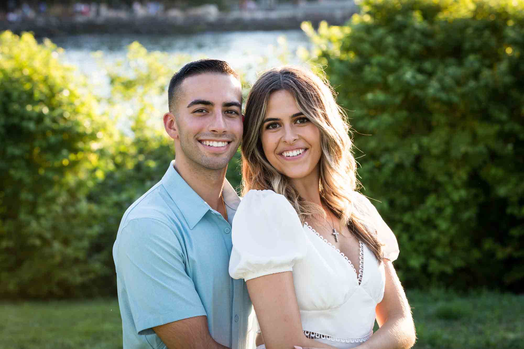 Couple hugging in grass in Brooklyn Bridge Park