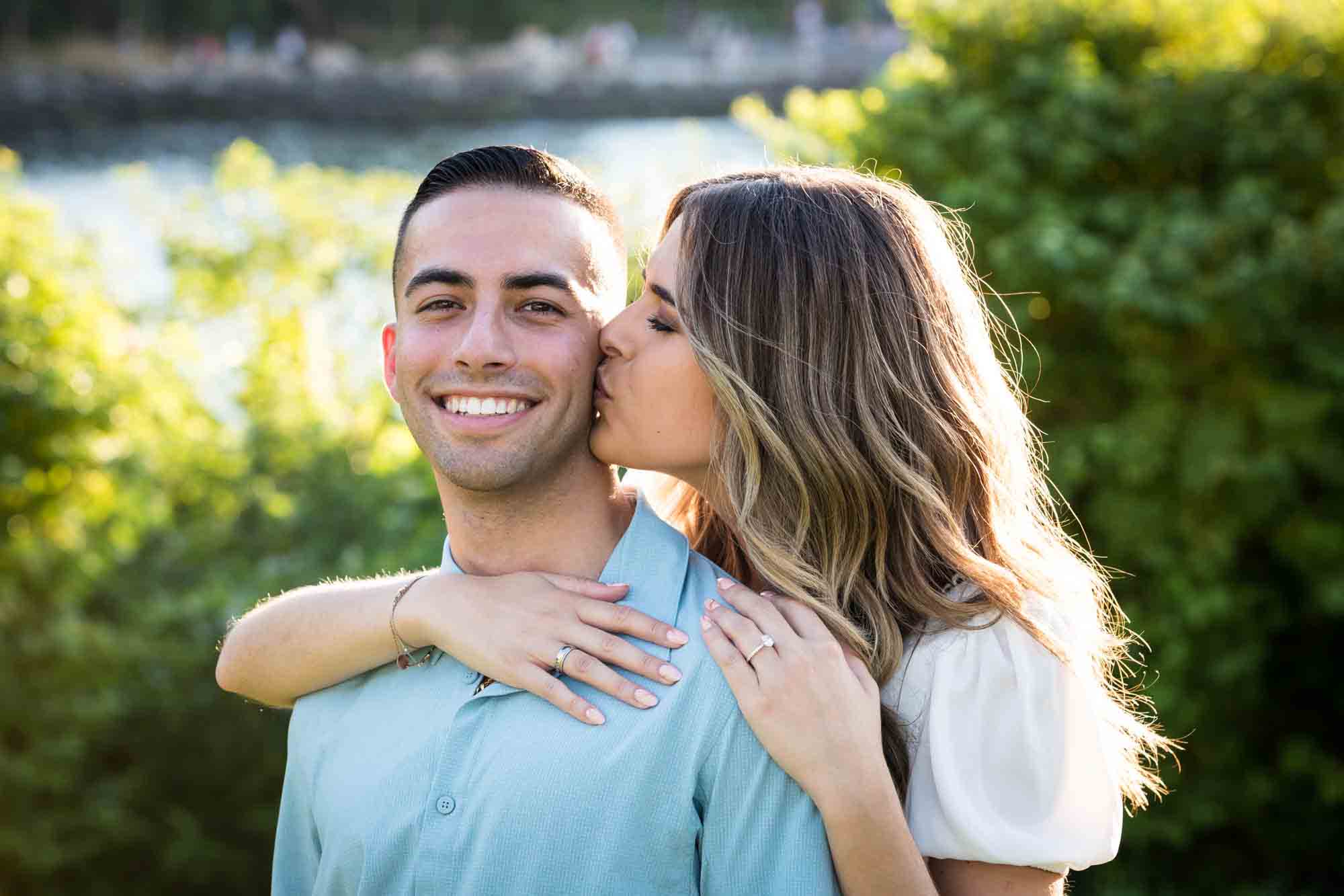 Woman kissing man on the cheek in Brooklyn Bridge Park