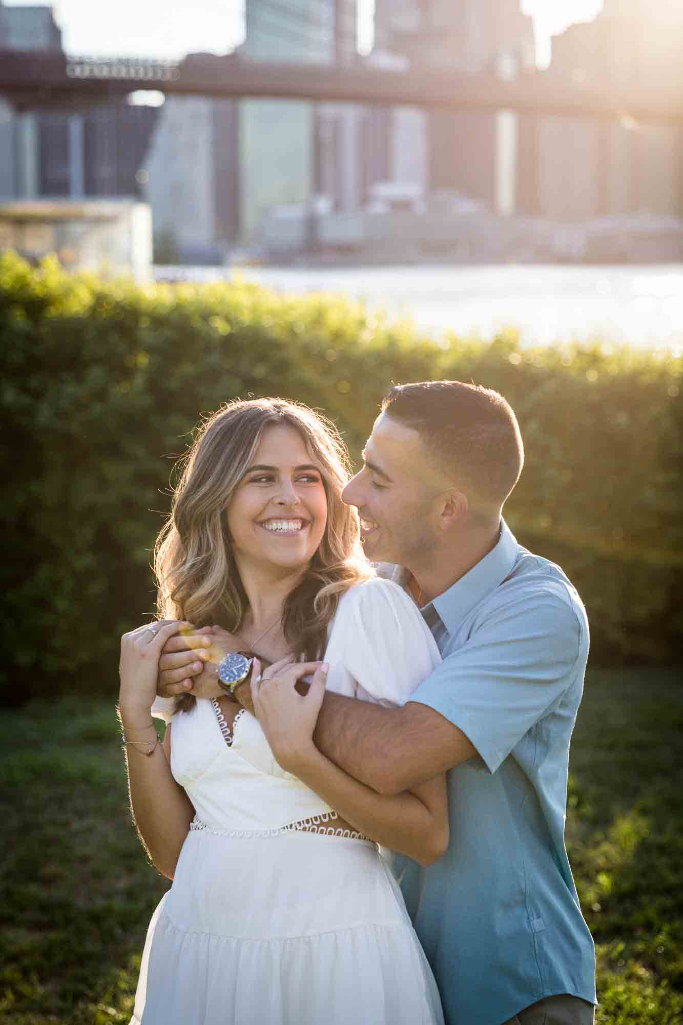 Couple hugging in grass in Brooklyn Bridge Park