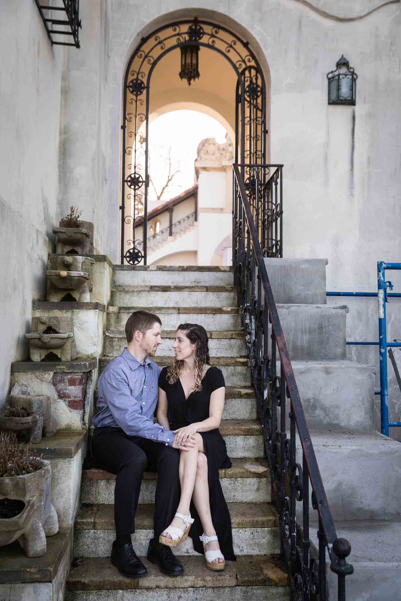 Couple sitting on stone steps at a Vanderbilt Museum engagement photo shoot