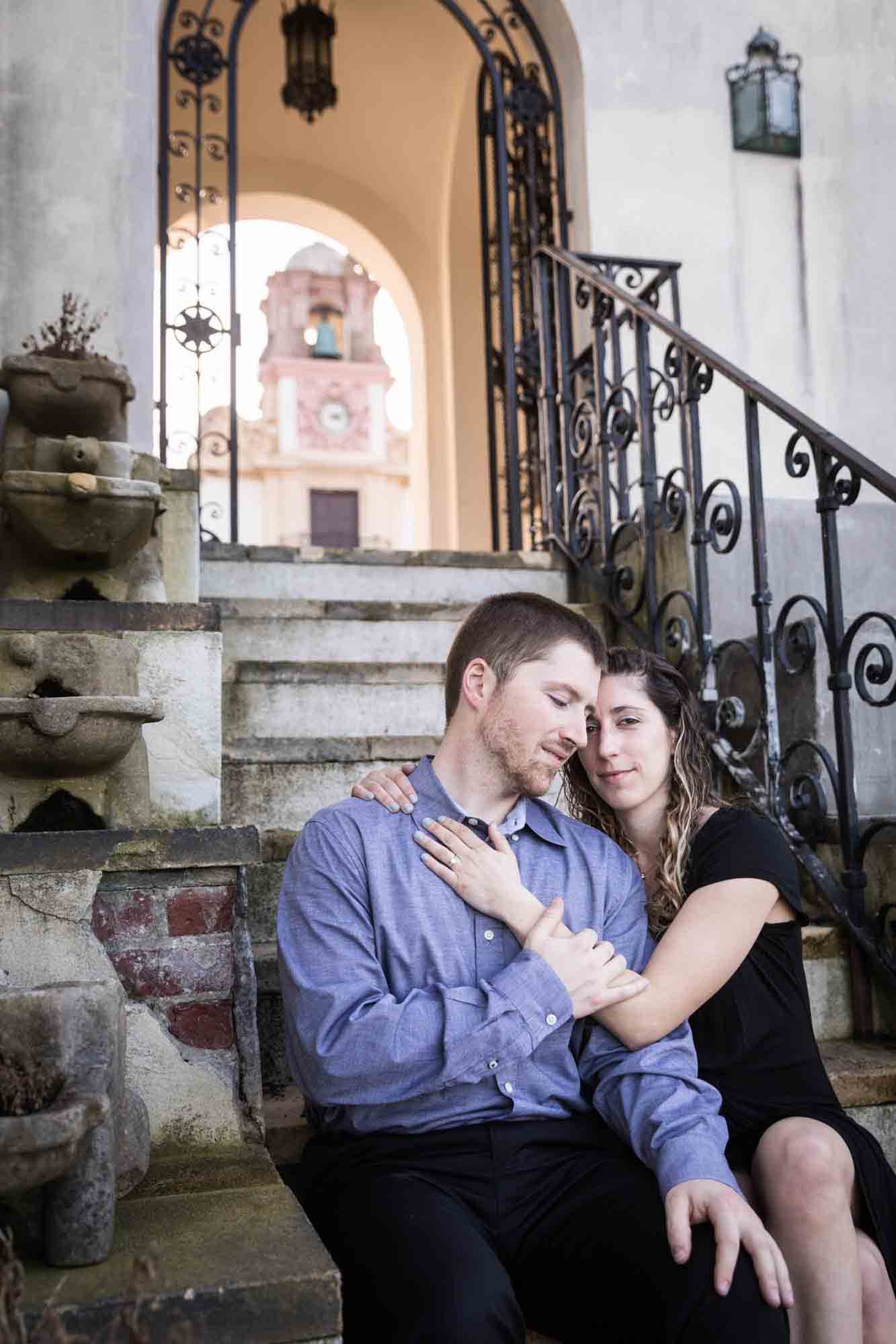 Couple cuddling on stone steps at a Vanderbilt Museum engagement photo shoot