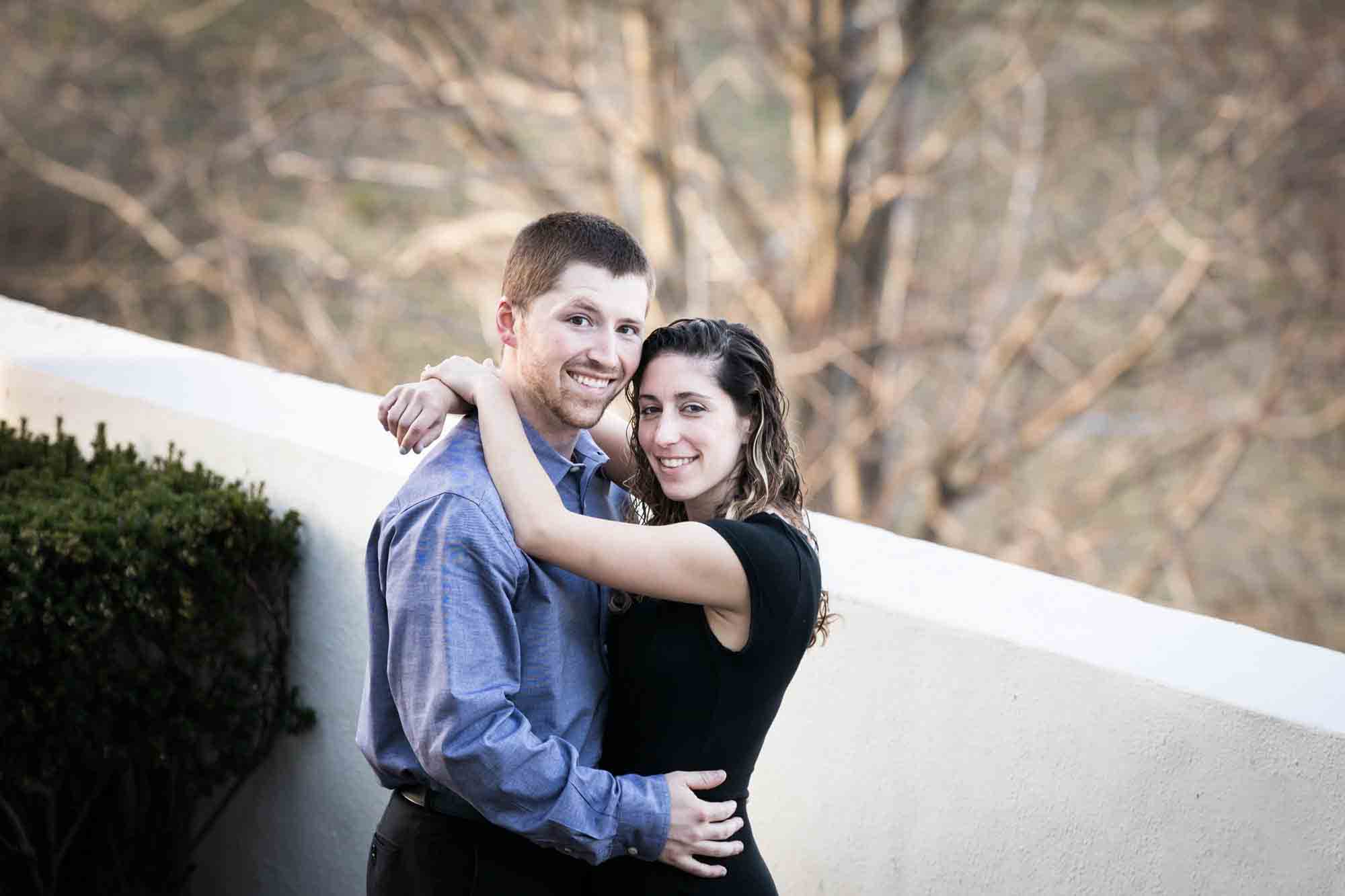 Couple hugging in front of white wall at a Vanderbilt Museum engagement photo shoot
