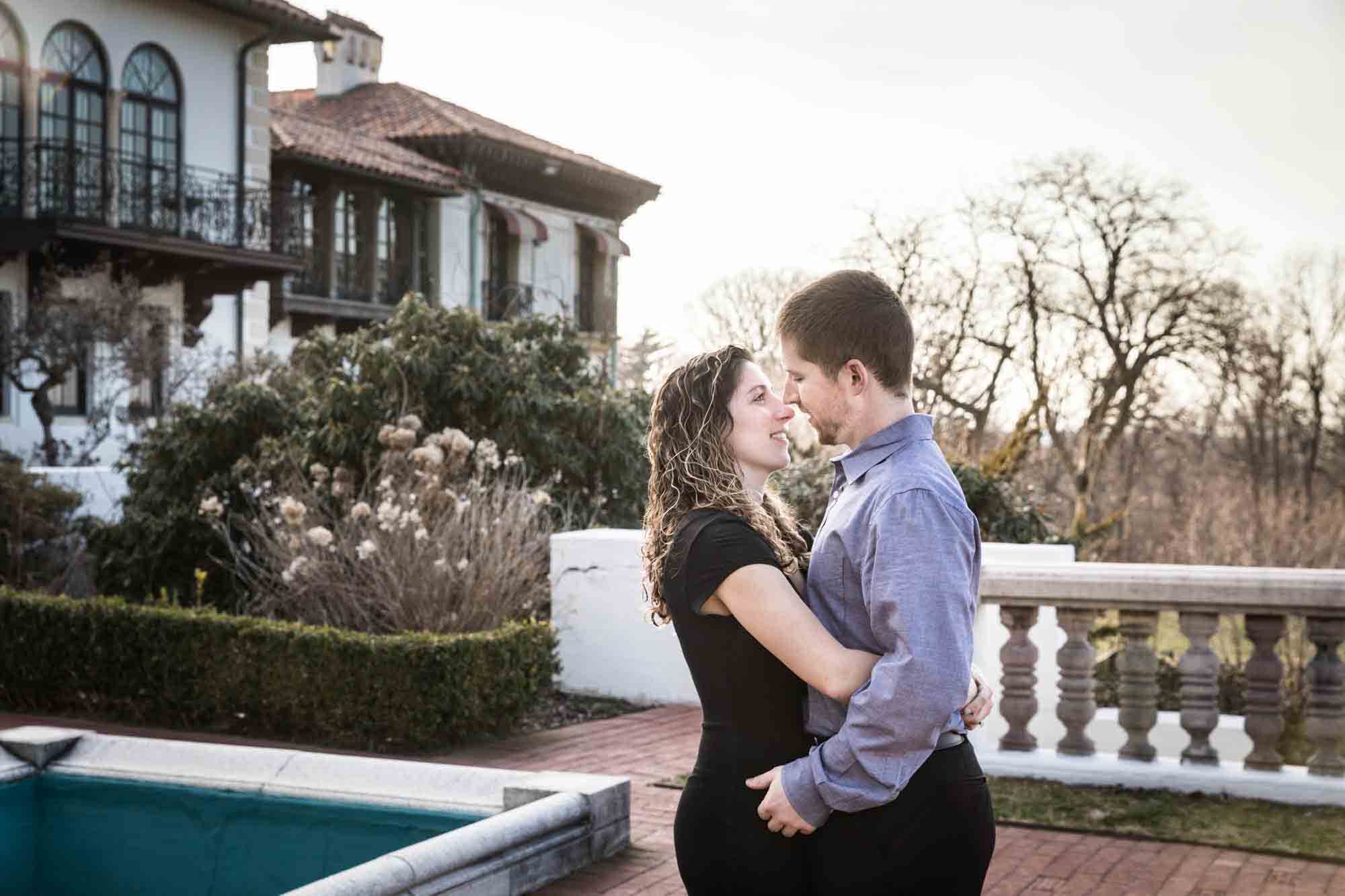 Couple cuddling in front of mansion during a Vanderbilt Museum engagement photo shoot