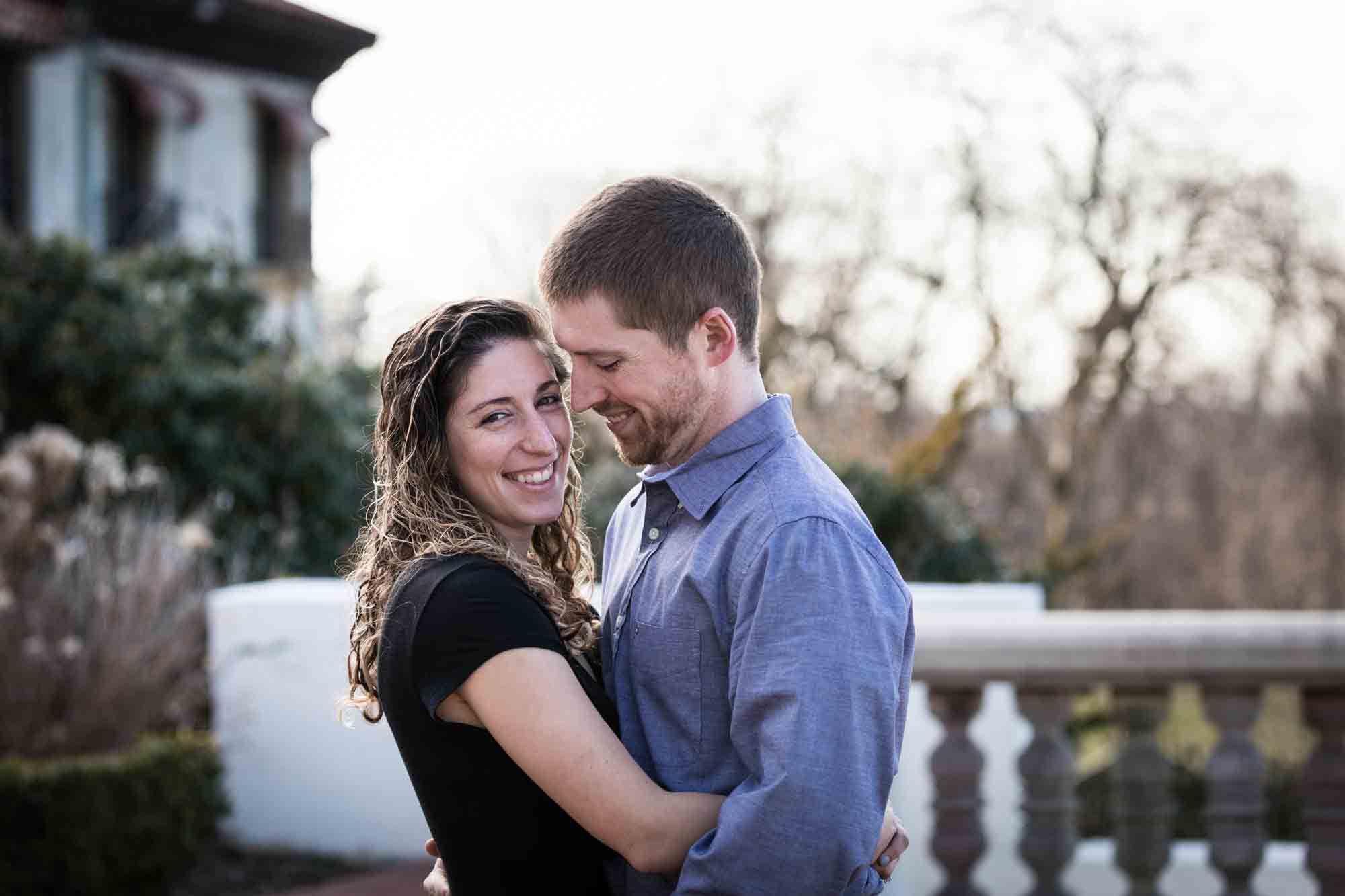 Couple cuddling in front of mansion during a Vanderbilt Museum engagement photo shoot