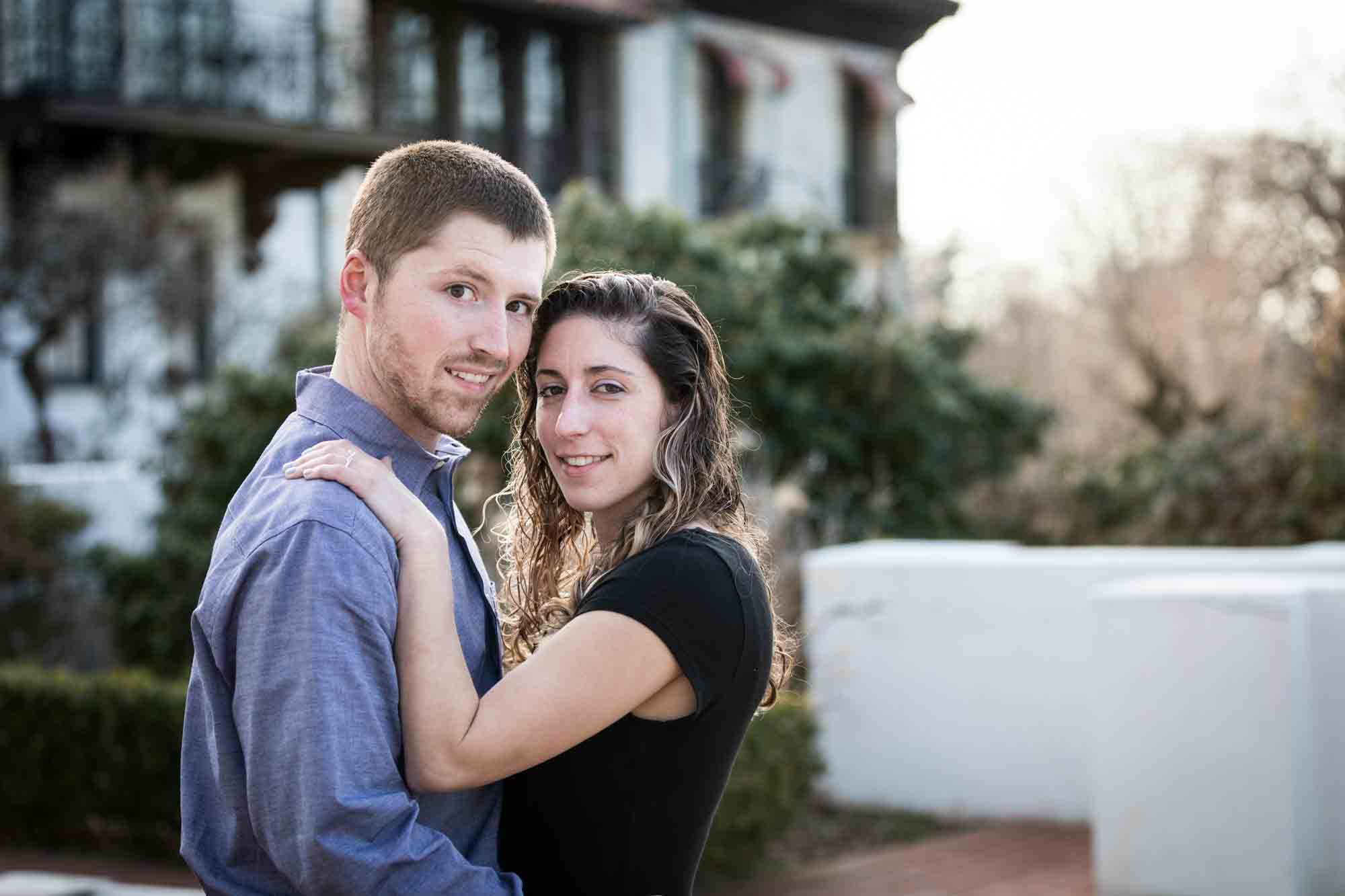 Couple cuddling in front of mansion during a Vanderbilt Museum engagement photo shoot