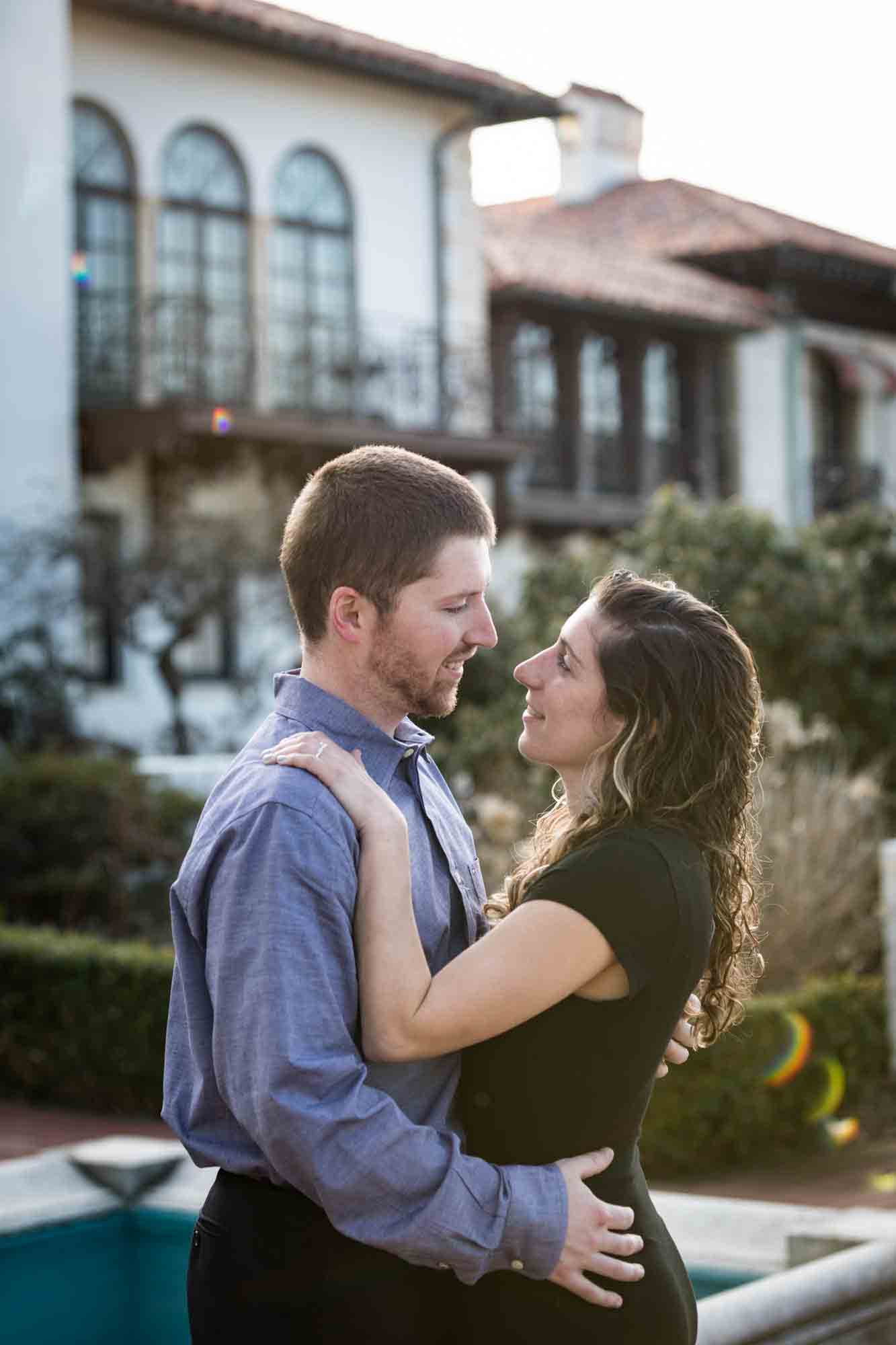 Couple cuddling in front of mansion during a Vanderbilt Museum engagement photo shoot