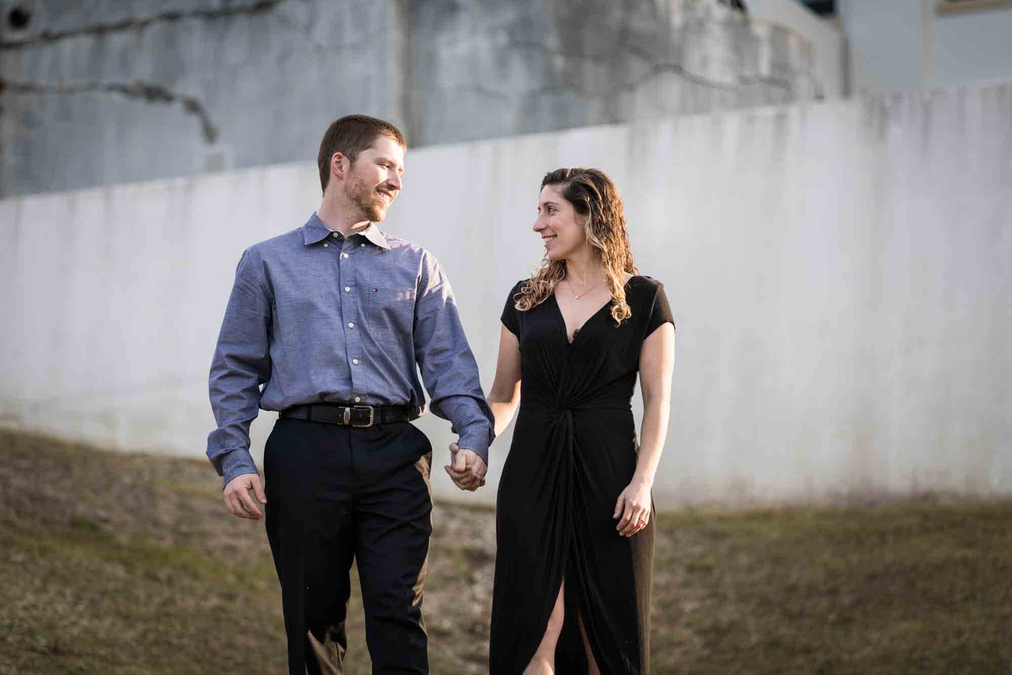 Couple walking hand in hand across grass at a Vanderbilt Museum engagement photo shoot