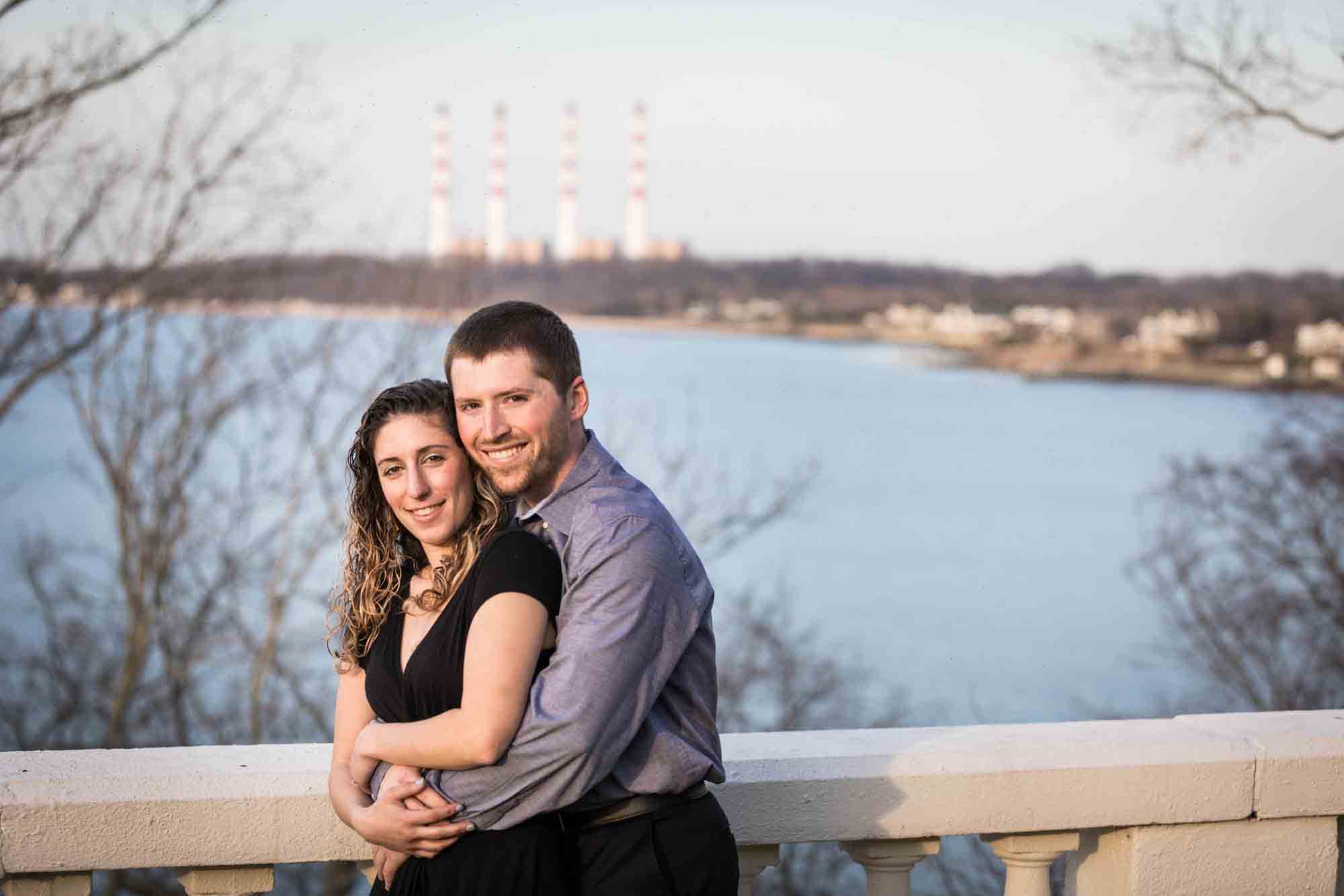 Vanderbilt Museum engagement photos of couple hugging on terrace overlooking Northport Bay