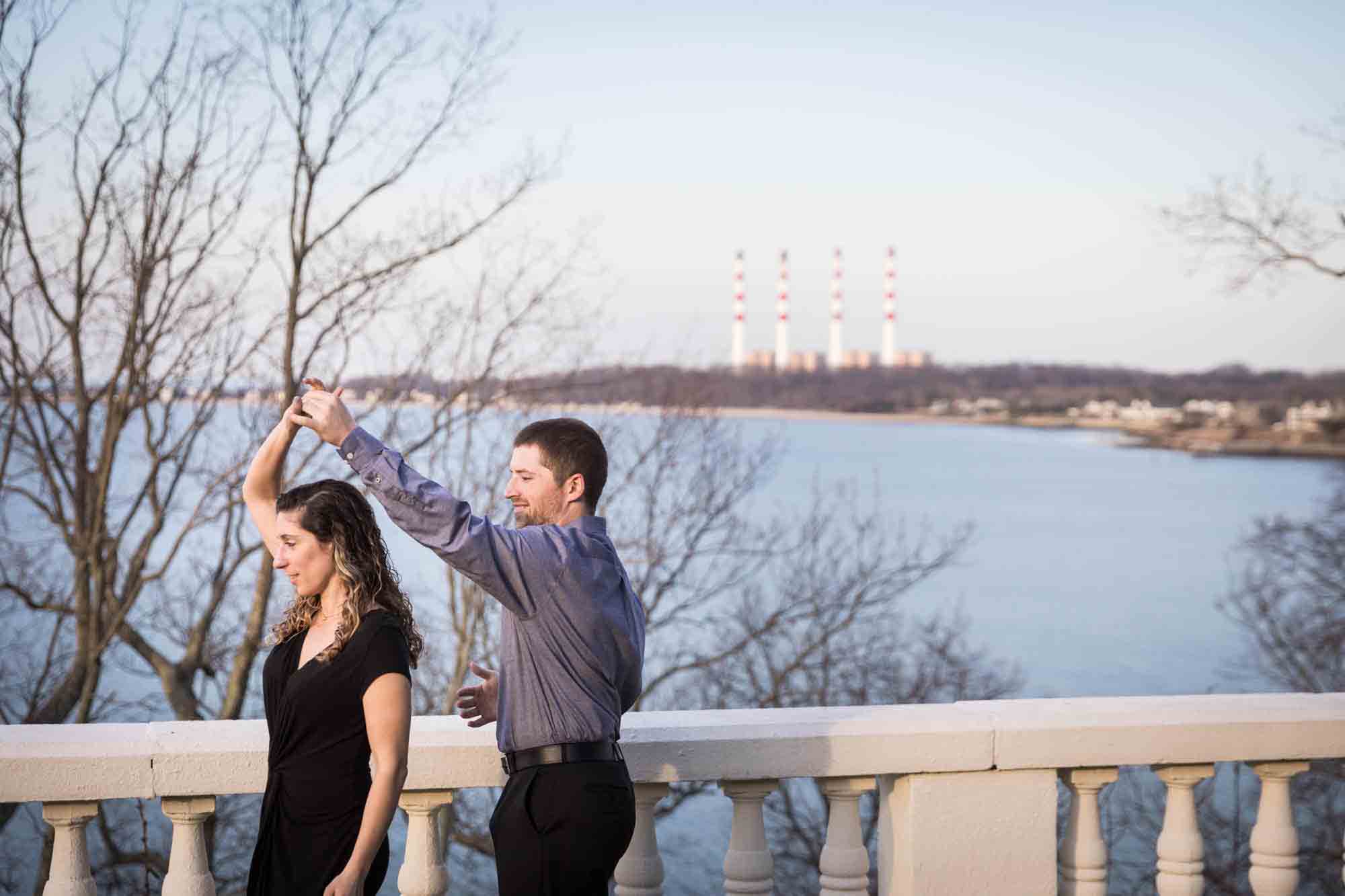 Vanderbilt Museum engagement photos of couple dancing on terrace overlooking Northport Bay