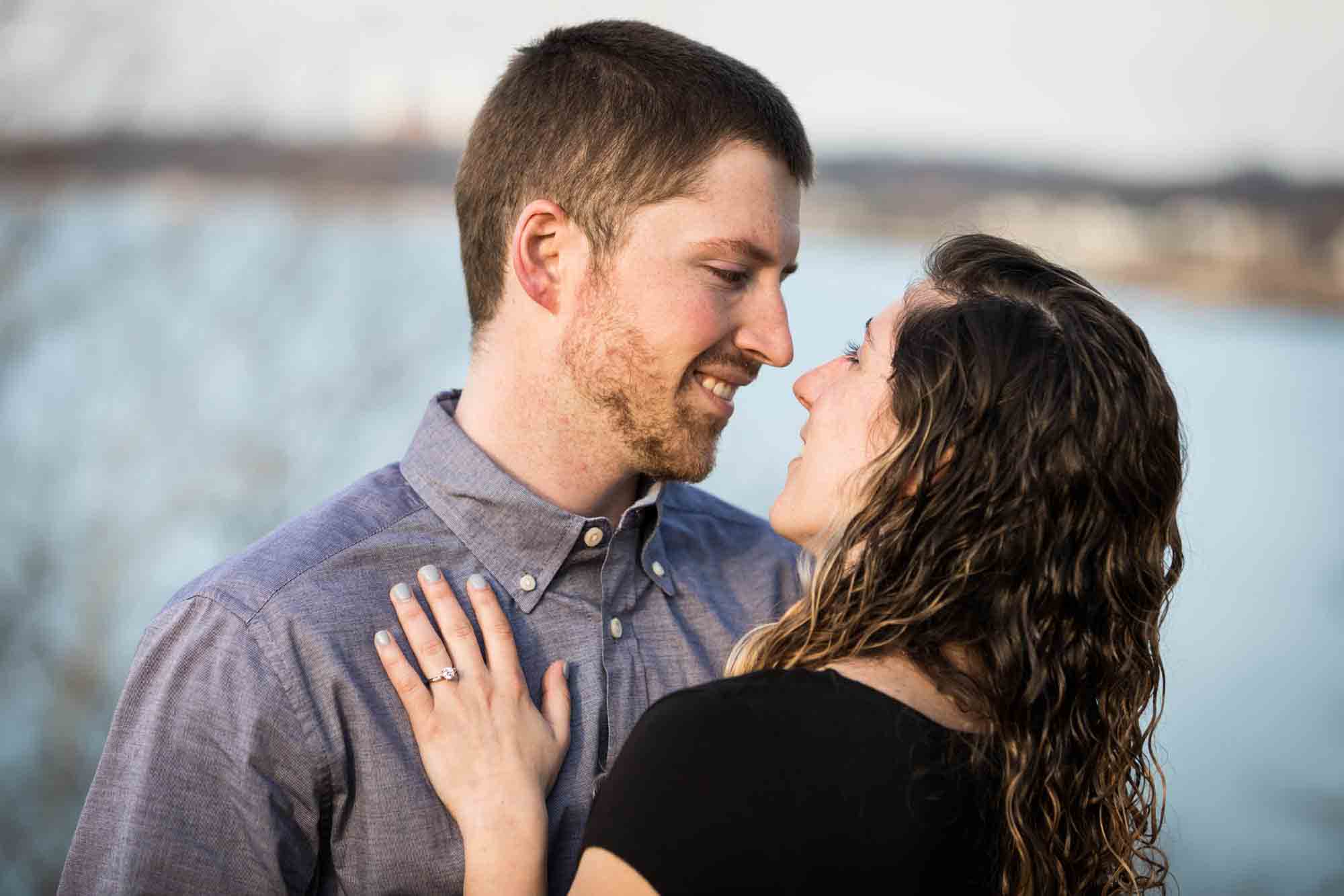 Vanderbilt Museum engagement photos of couple hugging with Northport Bay in background