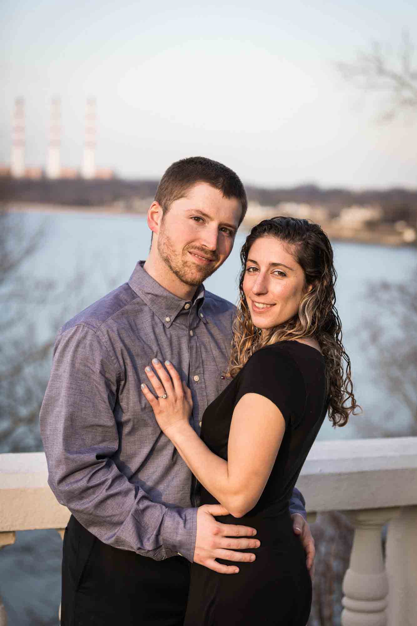 Vanderbilt Museum engagement photos of couple hugging on terrace overlooking Northport Bay
