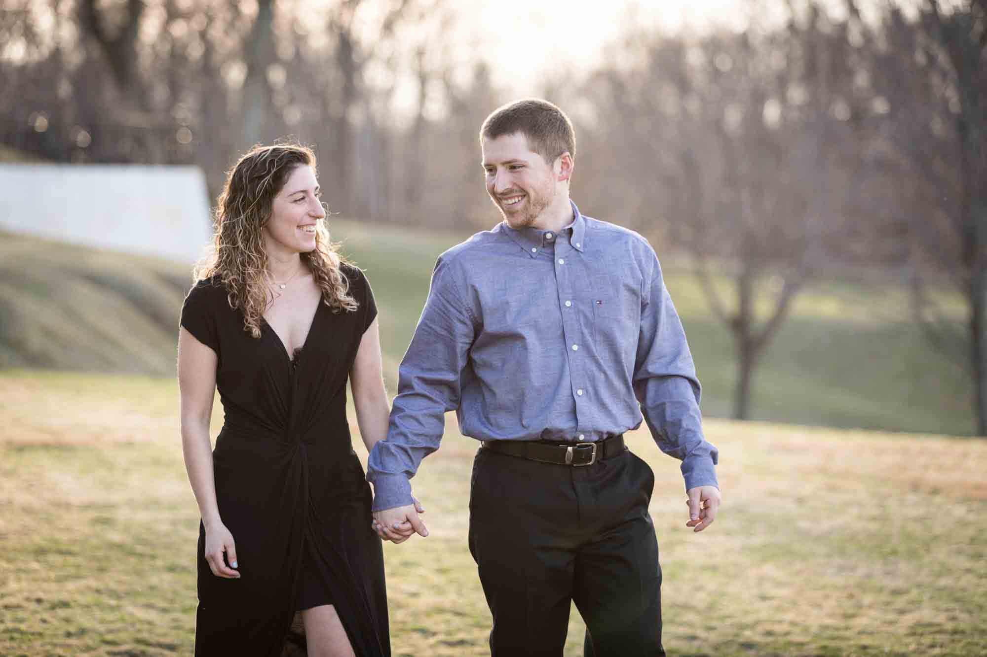 Vanderbilt Museum engagement photos of couple walking hand in hand across grass