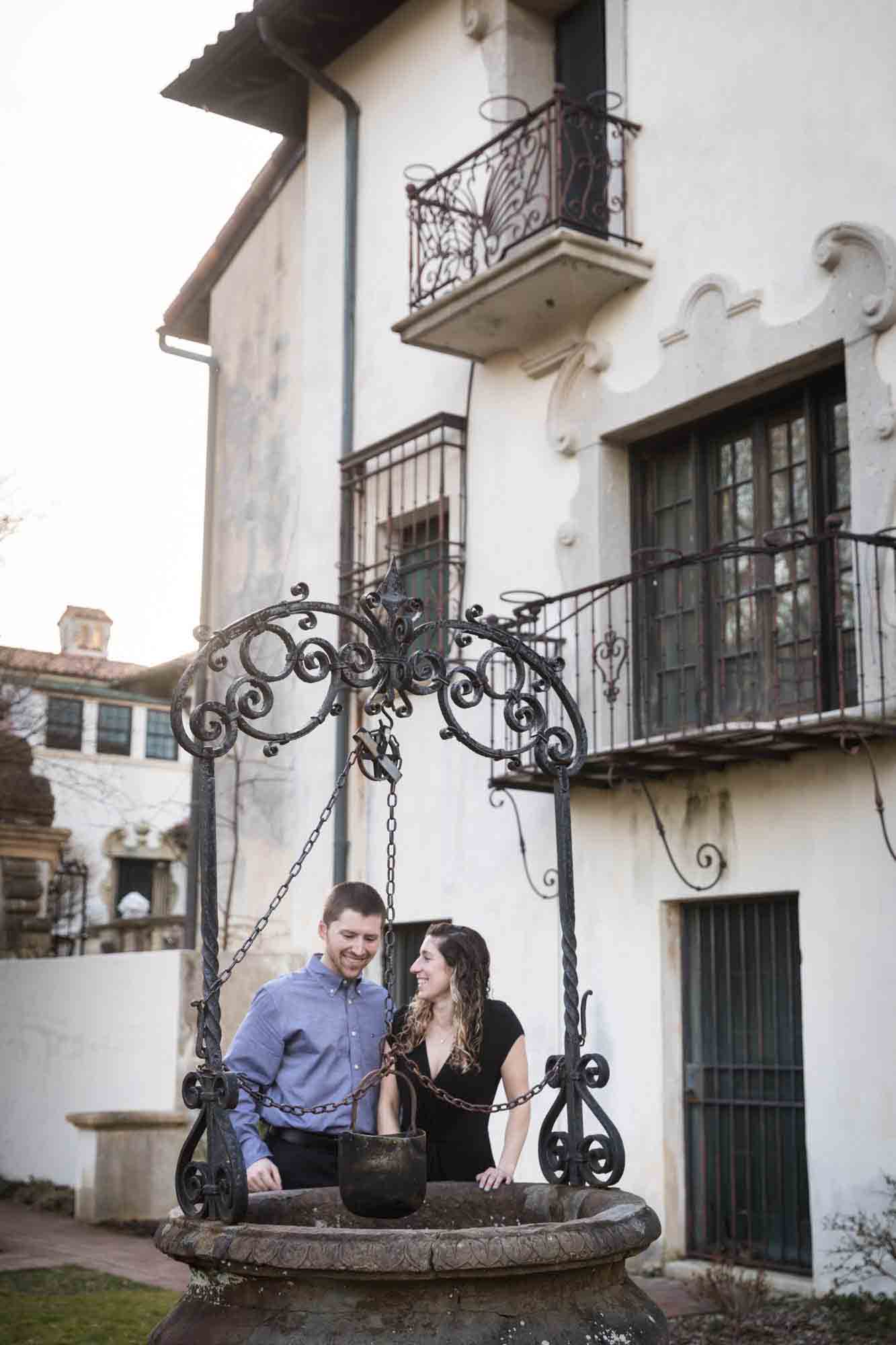 Vanderbilt Museum engagement photos of couple in front of well beside white building