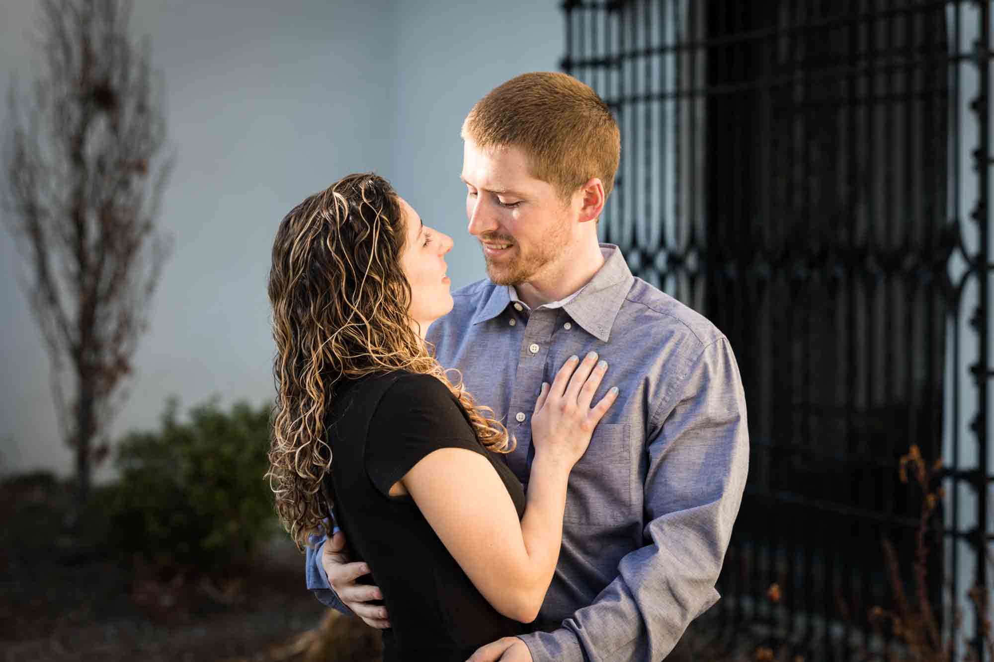 Couple cuddling in front of iron gate during a Vanderbilt Museum engagement photo shoot