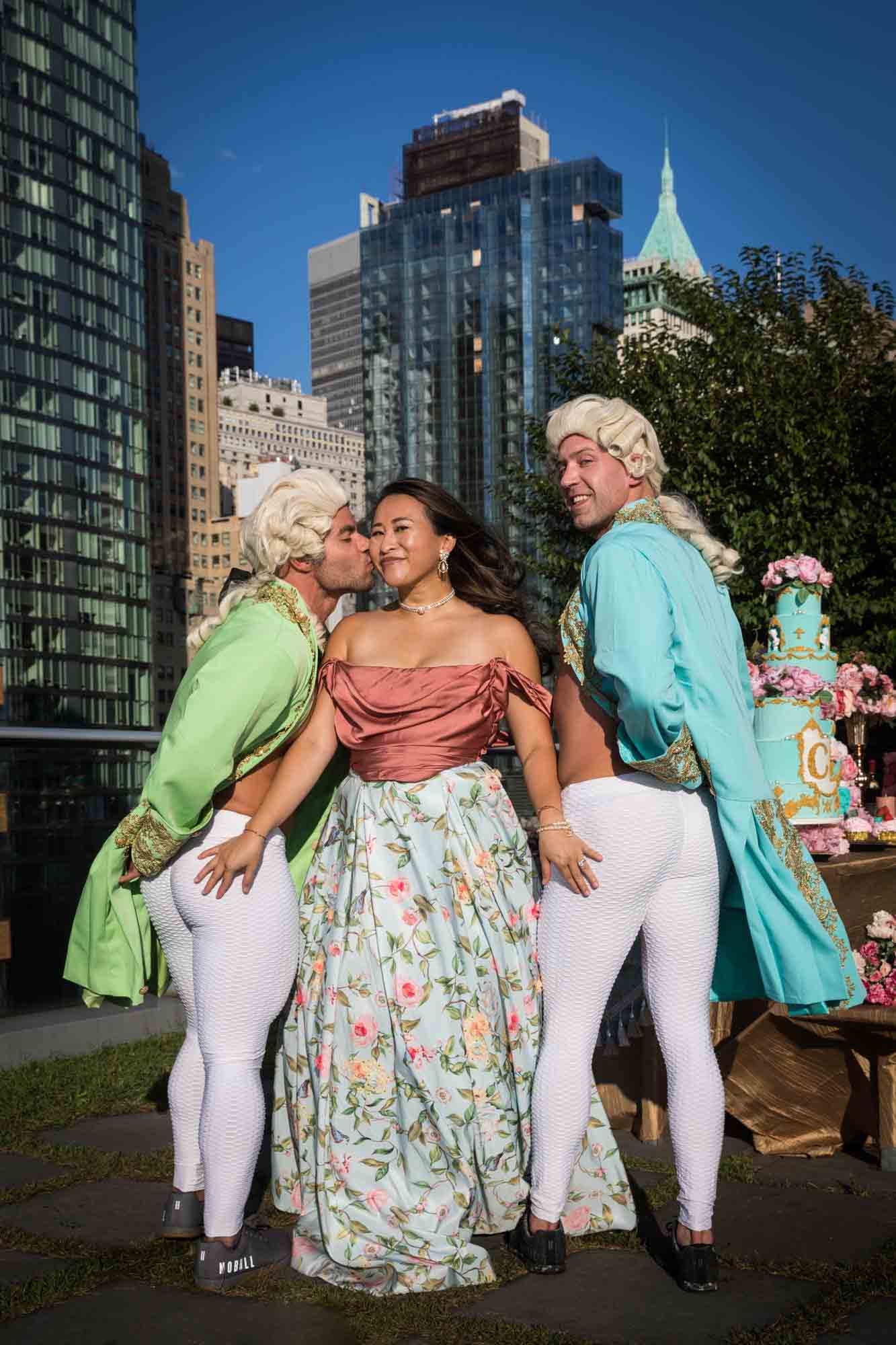 Woman dressed as Marie Antoinette with hands on the butts of men dressed as French courtiers for an article on event planning photography tips
