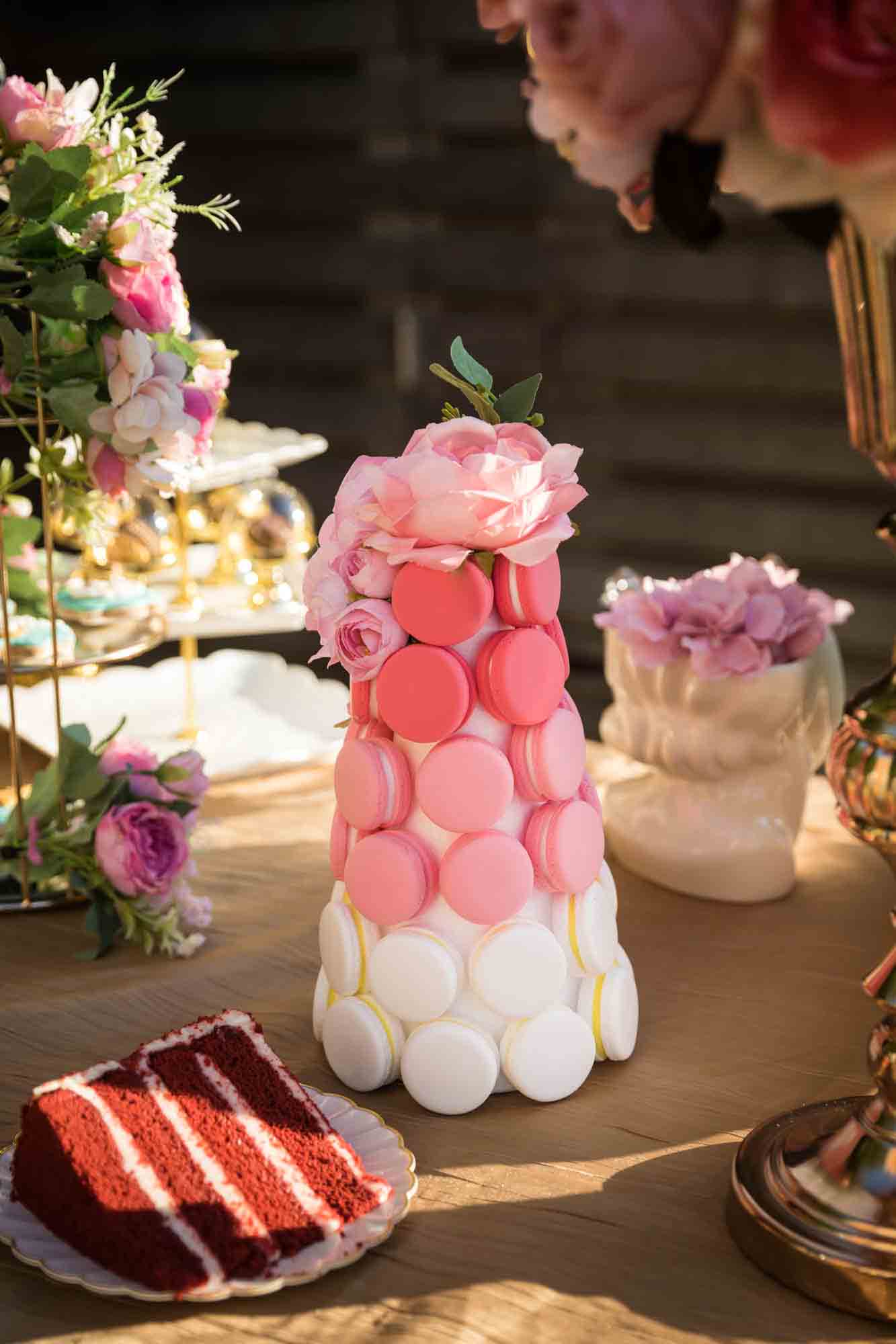 A tower of pink and white macarons on a table of elaborate desserts
