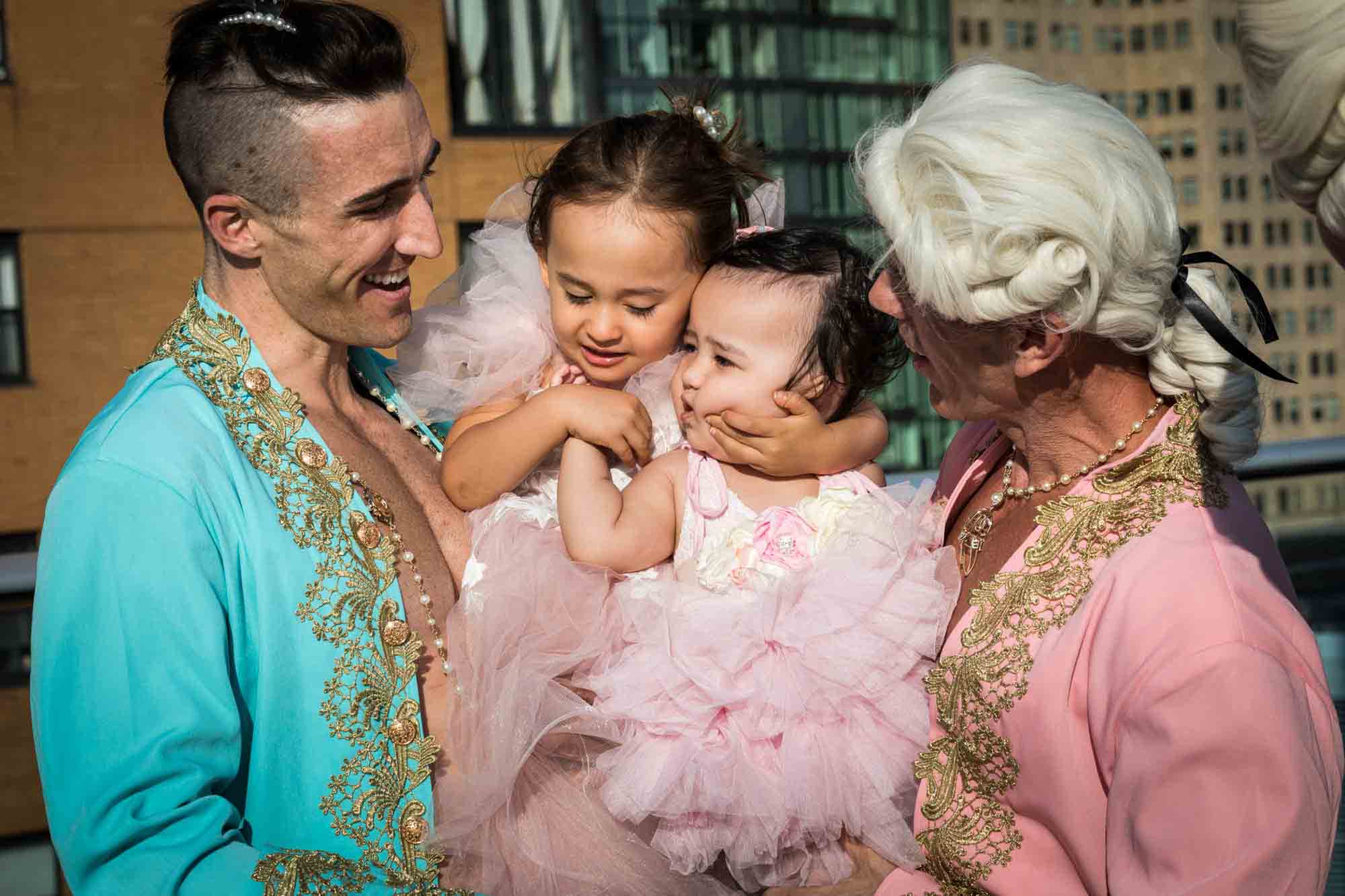 Two men dressed as French courtiers holding two little girls wearing pink dresses for an article on event planning photography tips