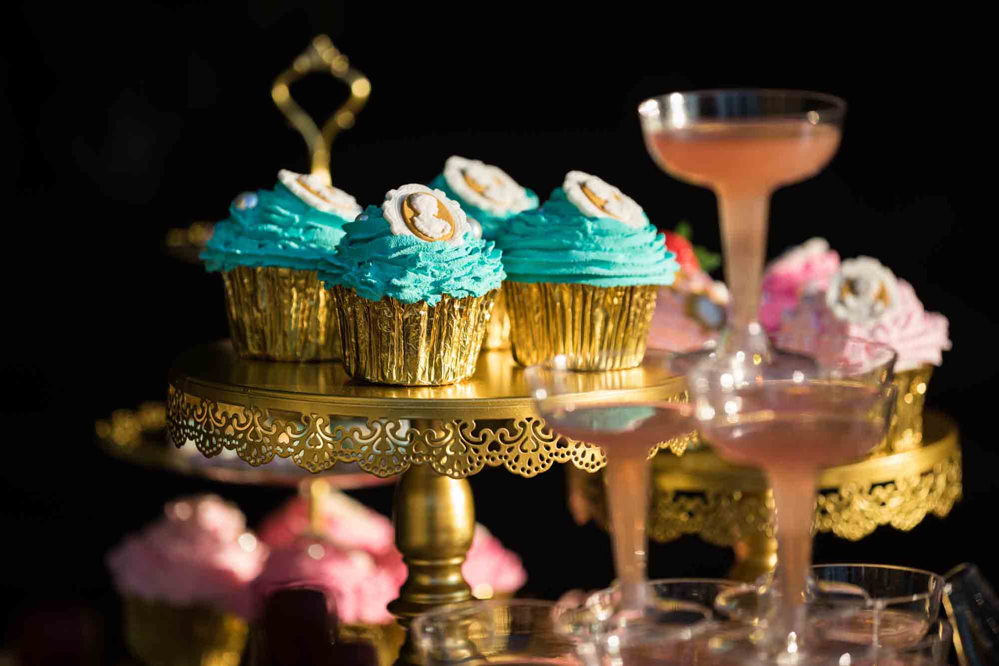 Tower of aqua and pink frosted cupcakes on a table of elaborately decorated desserts