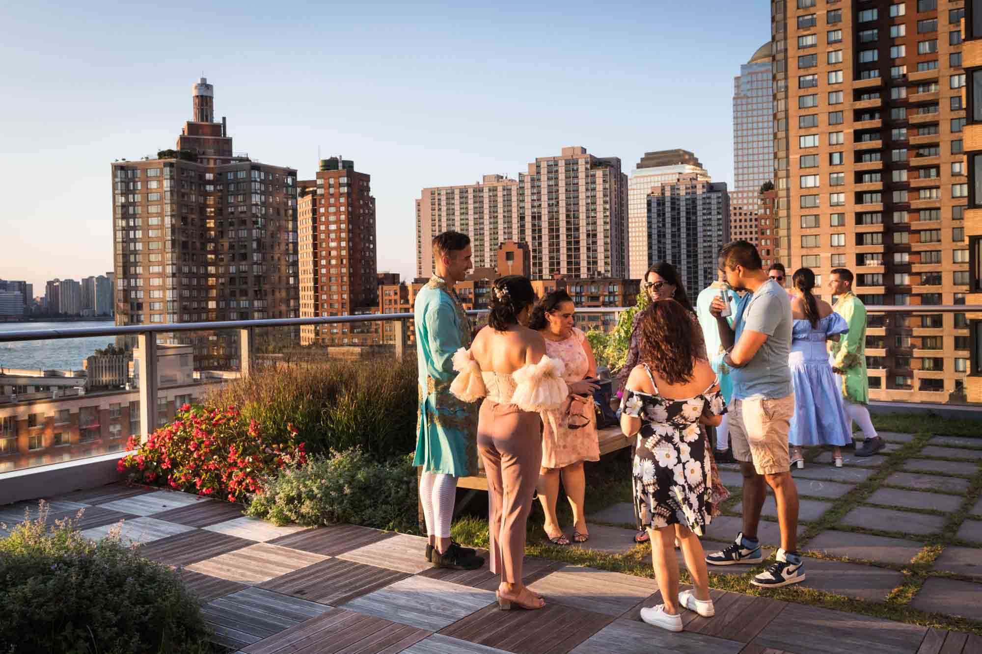 Guests enjoying a Marie Antoinette-themed party on an outdoor patio with view of NYC skyscrapers