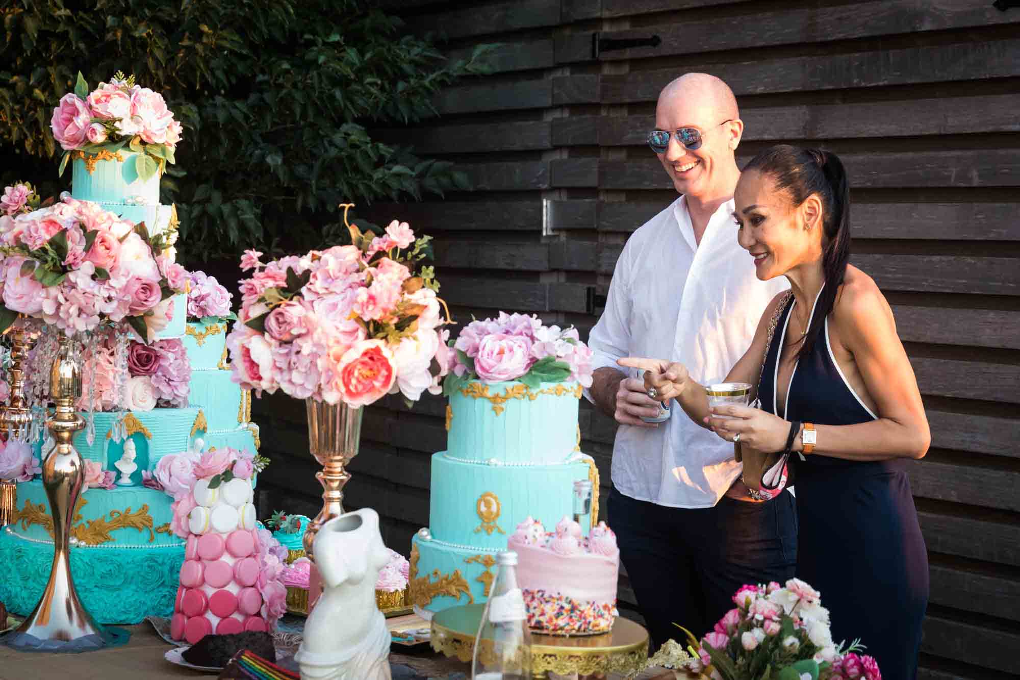 Couple smiling while looking at table of elaborately-decorated desserts