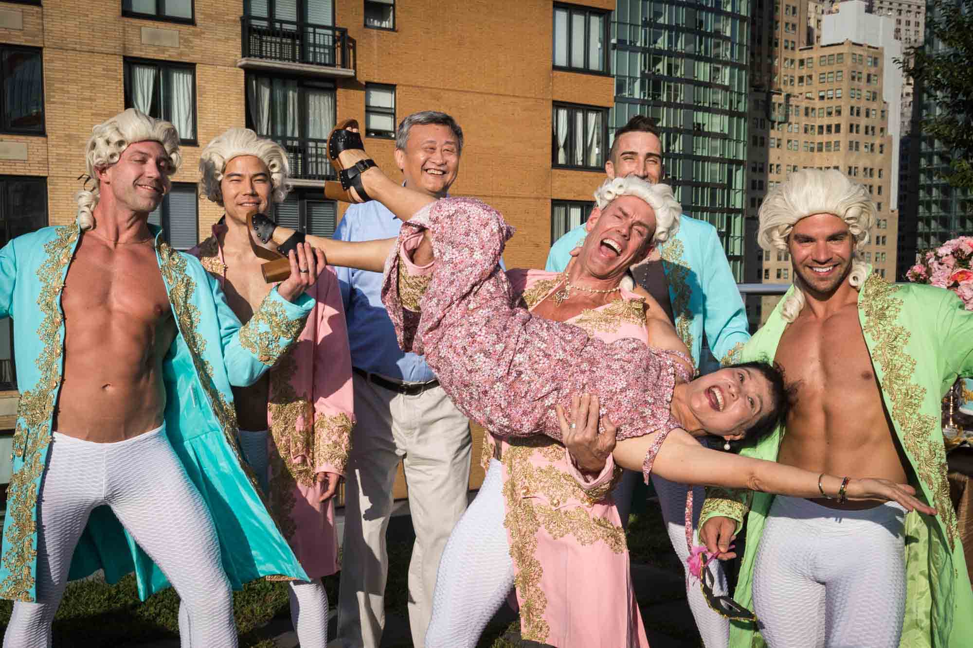 Men dressed as French couriers holding an Asian American woman upside down for an article on event planning photography tips