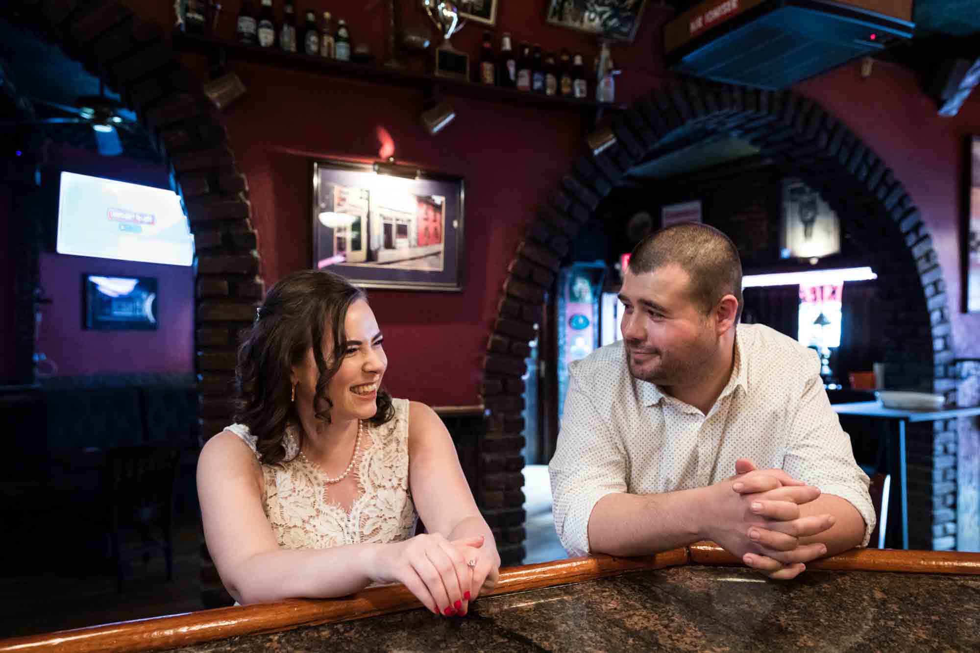 Couple sitting at bar looking at each other for an article on how to recreate your love story in your engagement shoot