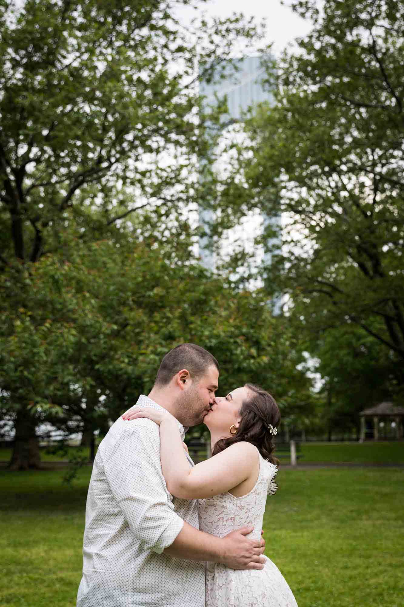 Couple kissing in front of trees during a Dyker Heights engagement shoot