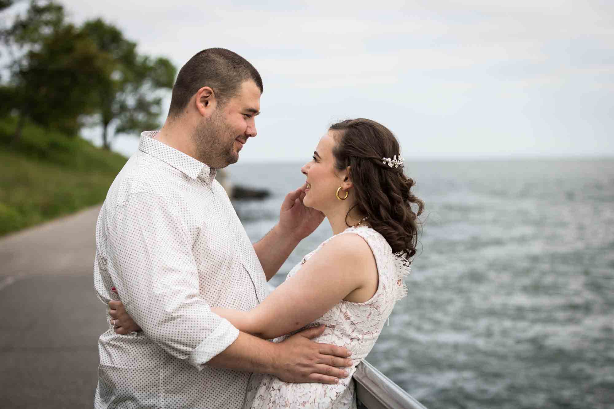 Couple hugging with man touching woman's cheek during a Dyker Heights engagement shoot