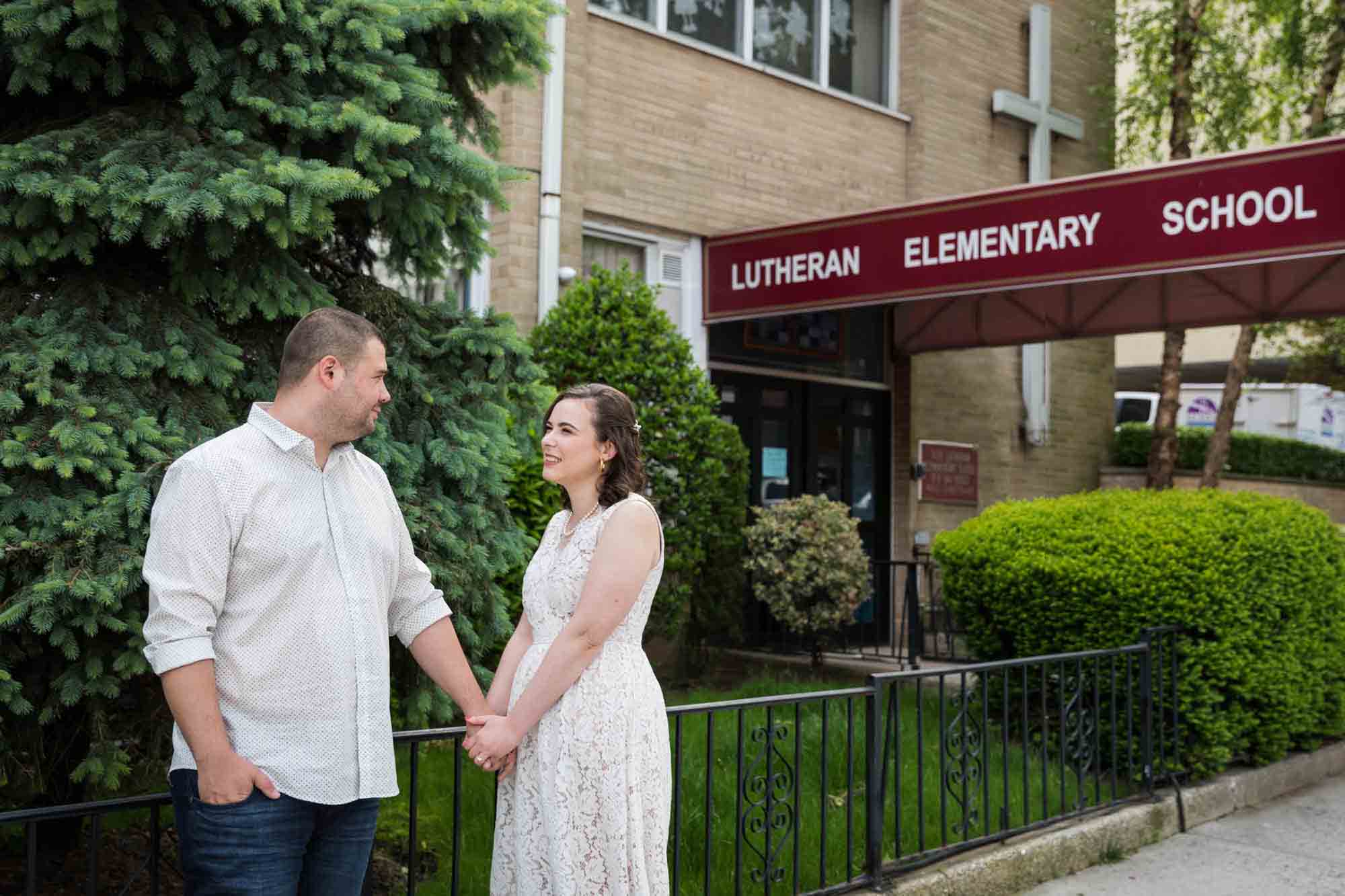 Couple holding hands in front of Lutheran Elementary School for an article on how to recreate your love story in your engagement shoot