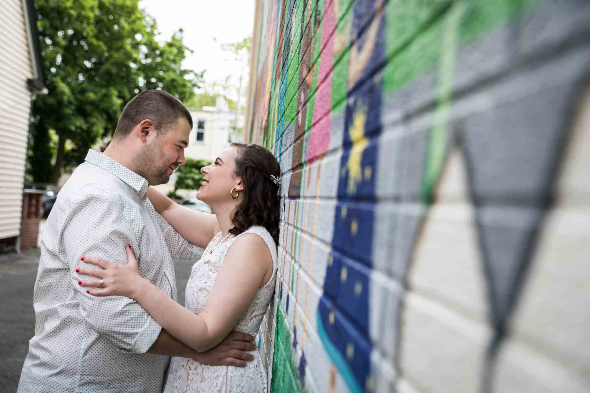 Couple hugging in front of colorful wall mural for an article on how to recreate your love story in your engagement shoot