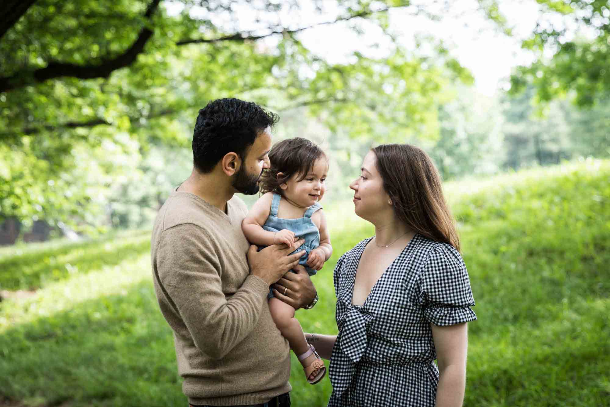 Parents focused on toddler in father's arms during a Fort Green Park family photo shoot