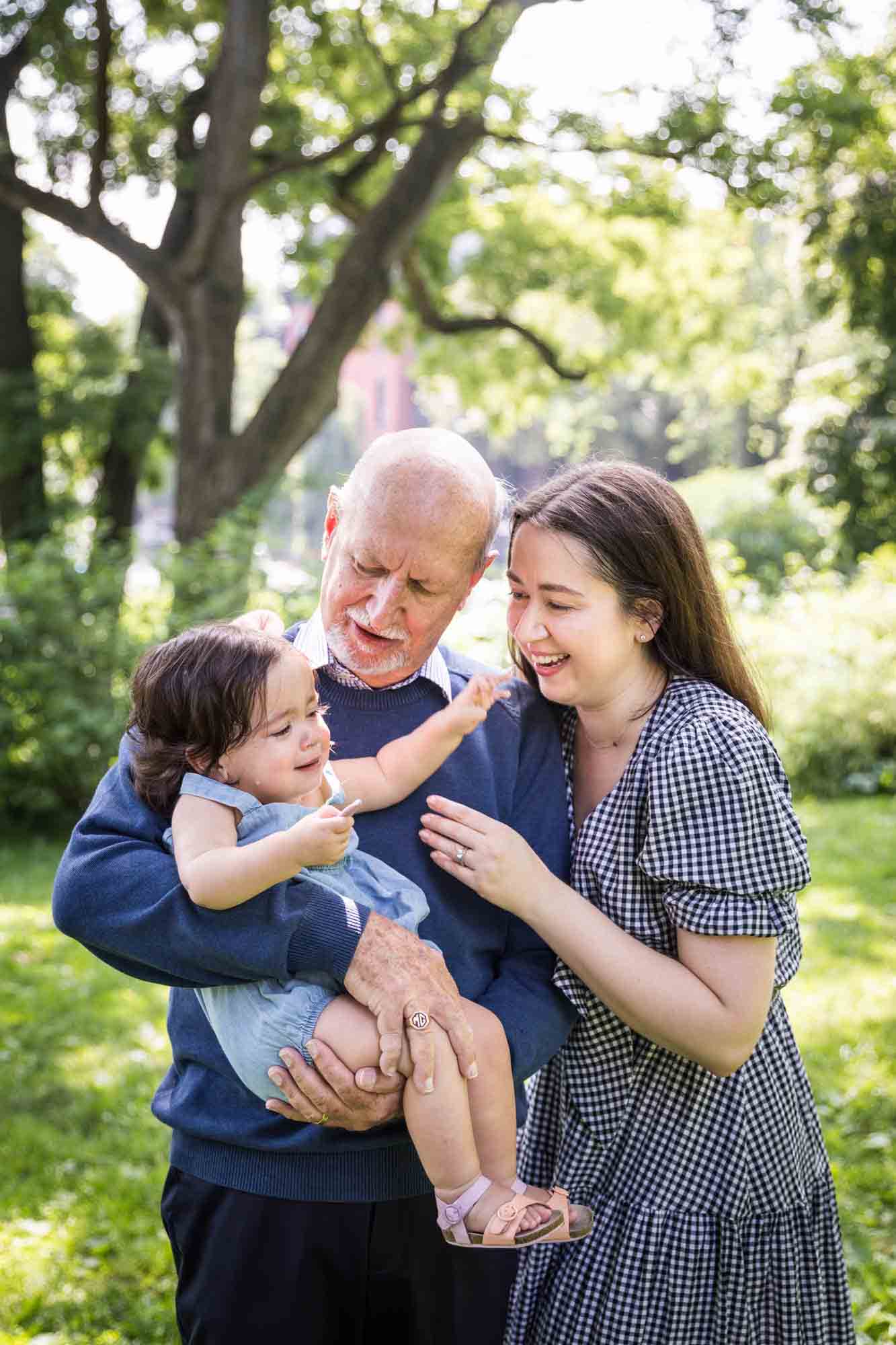 Grandfather and mother playing with baby girl during a Fort Greene Park family portrait