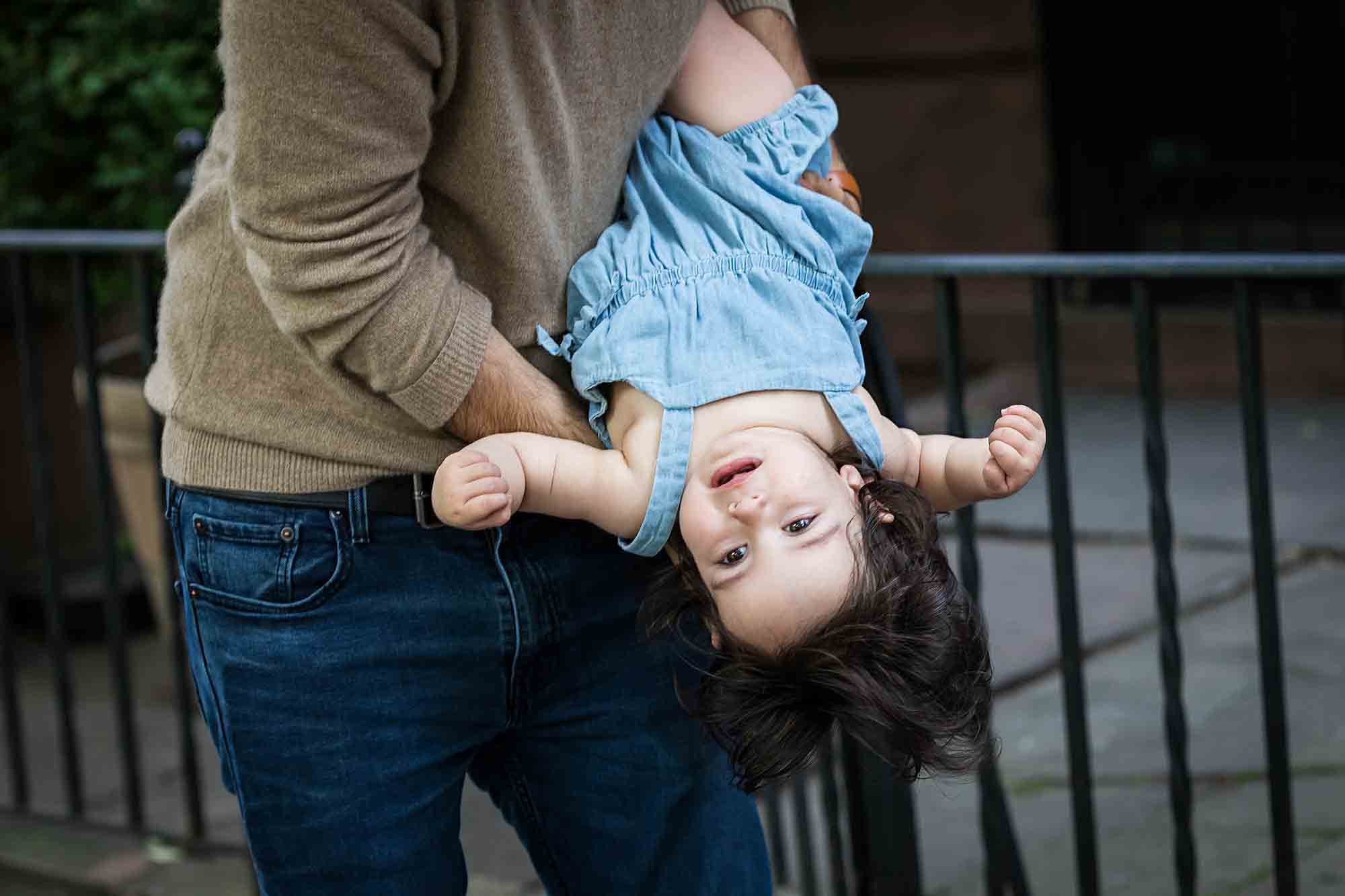 A little girl held upside down by her father for an article on how to solve family portrait challenges