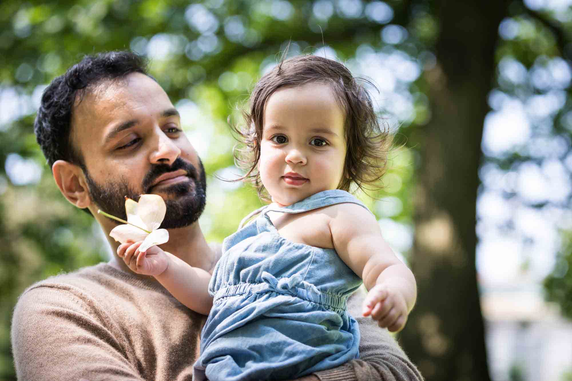 Father holding little girl holding flower in hand during a Fort Greene Park family portrait