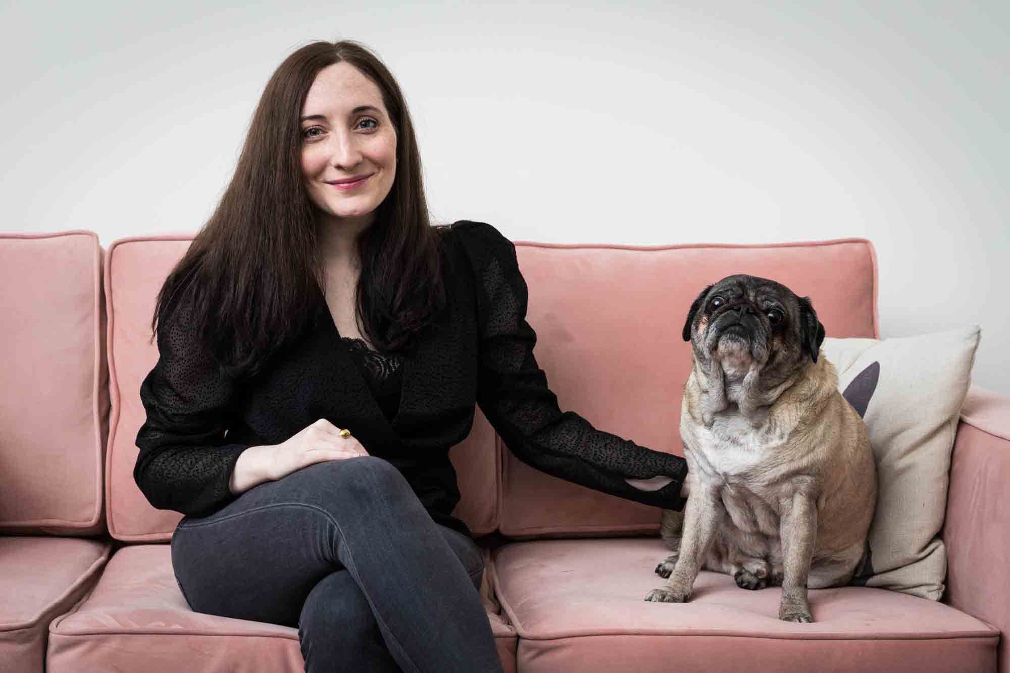Author Jiordan Castle sitting on pink couch with pug dog