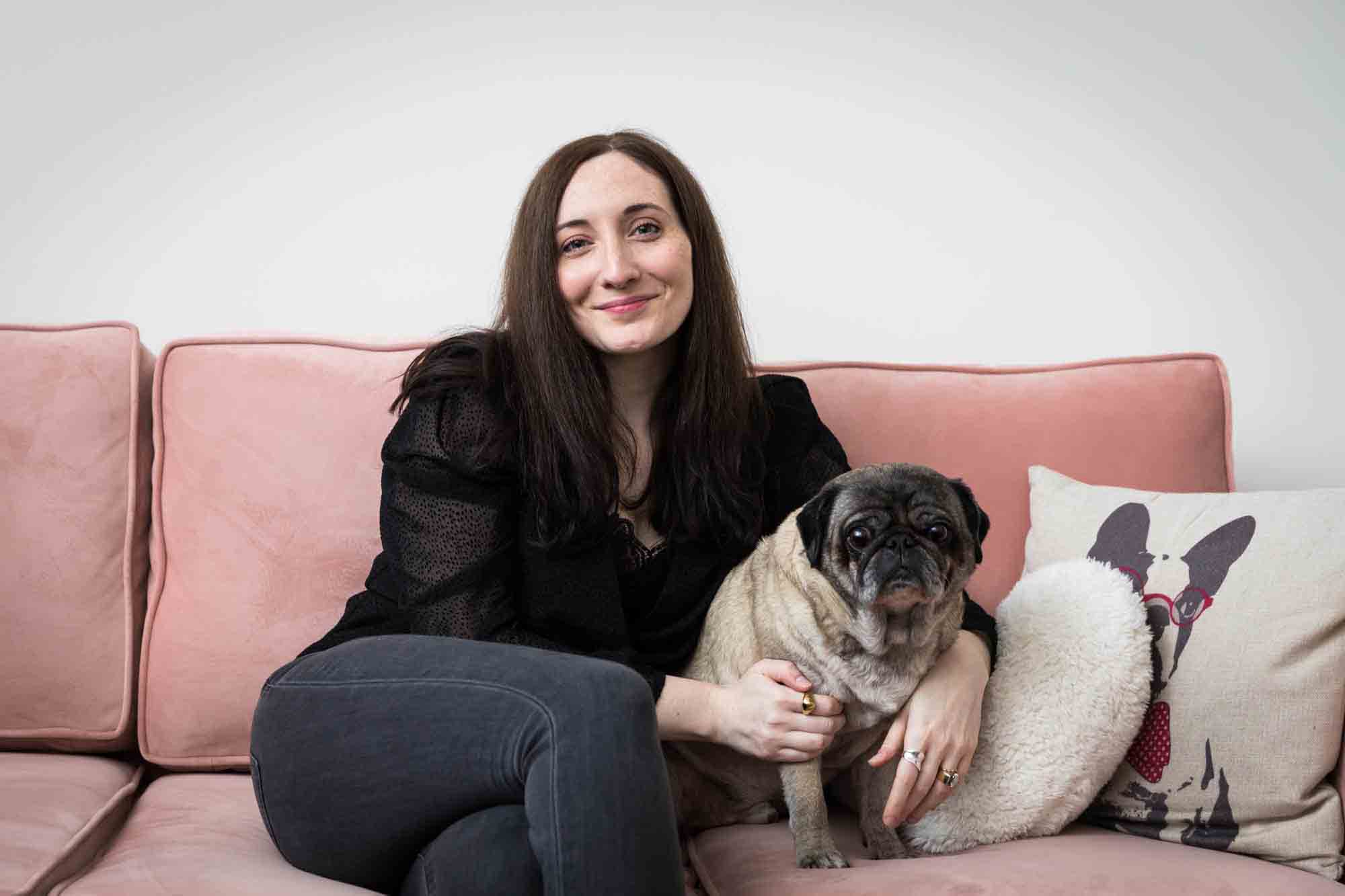 Author Jiordan Castle sitting on pink couch with pug dog