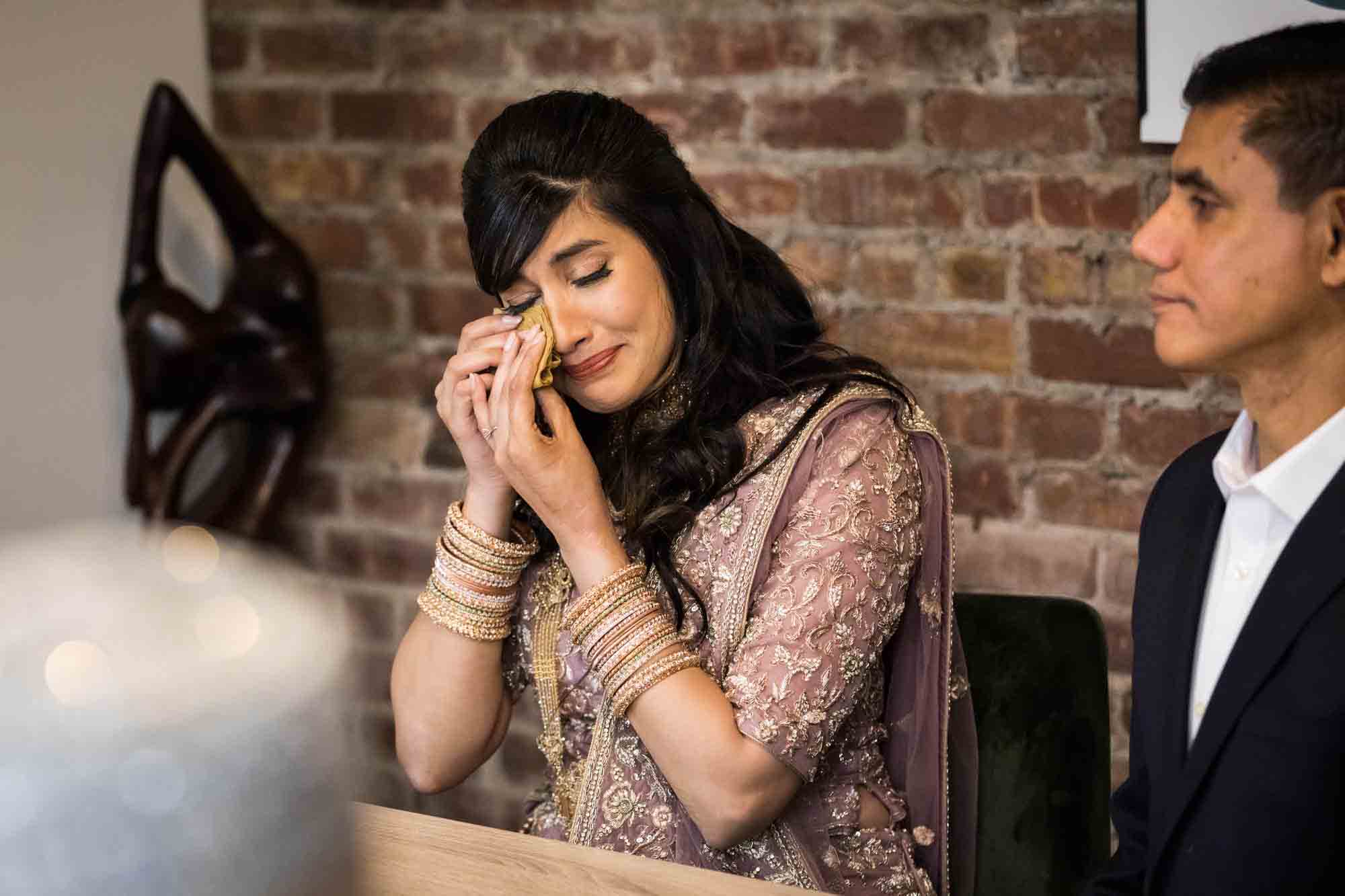 Bride wiping away tears during nikkah wedding ceremony