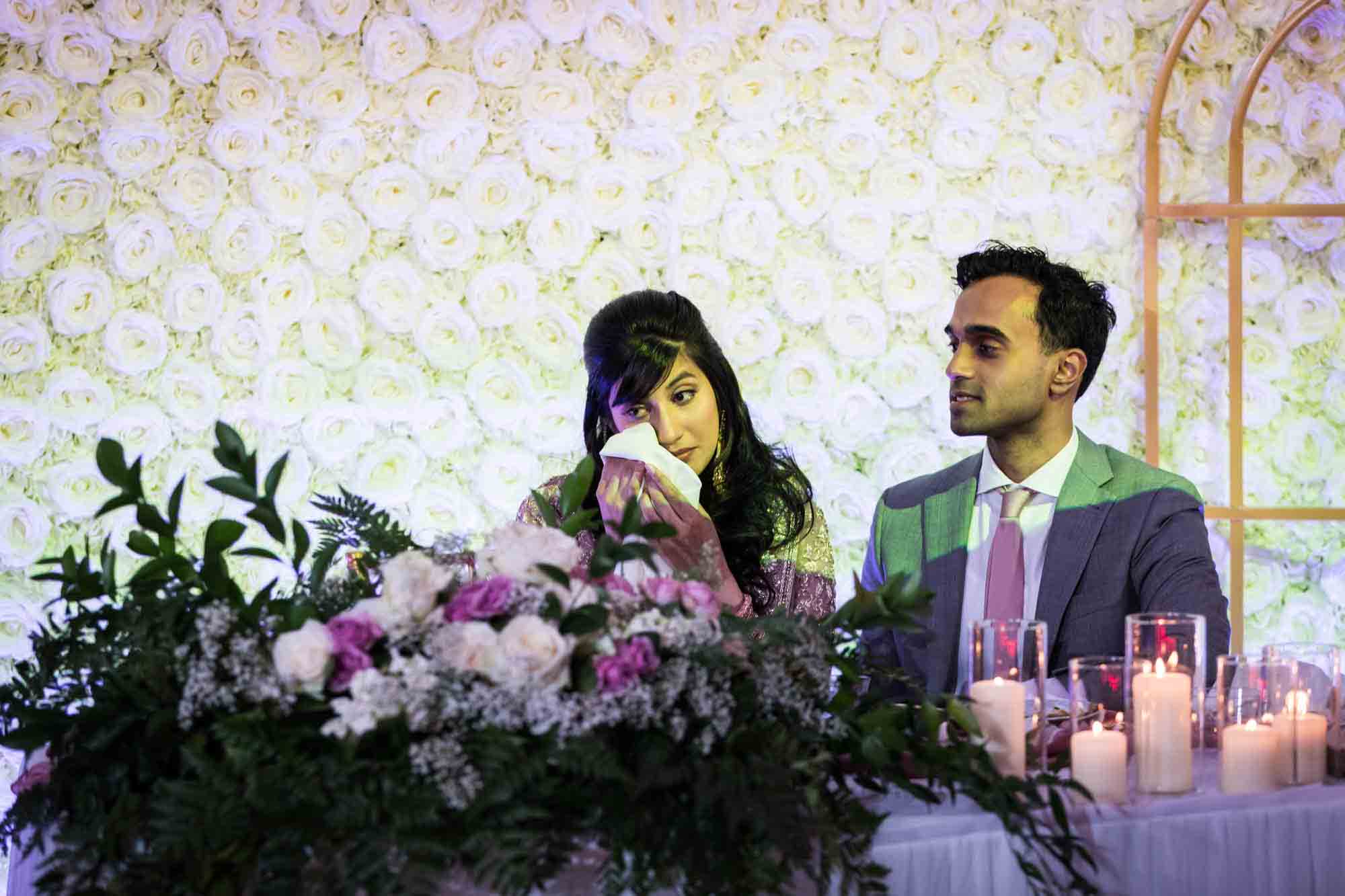 Indian bride wiping away tear with groom at table at a Loft Story wedding