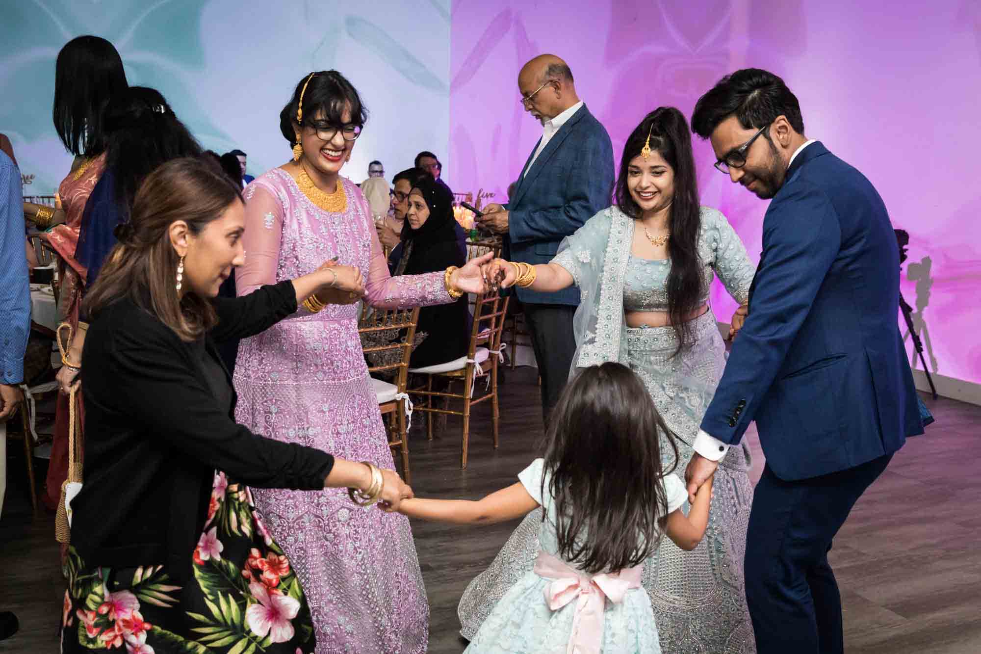 Family dancing together while holding hands Bride and groom holding up shoes on dance floor for article on wedding reception game ideas