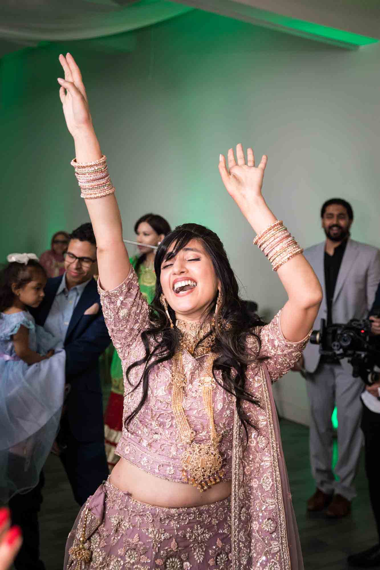 Indian bride dancing with hands raised at a Loft Story wedding