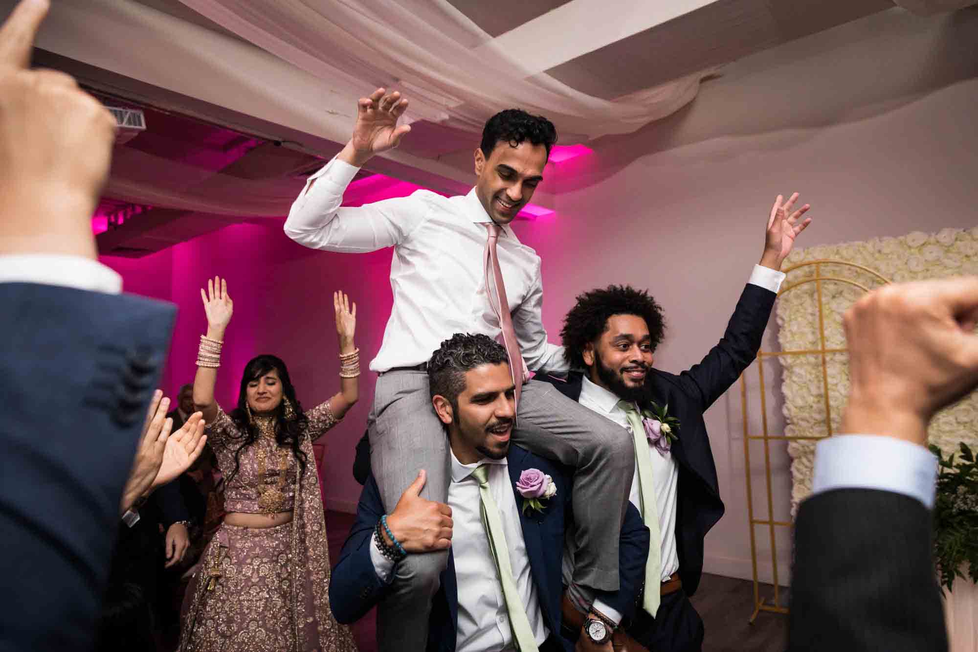 Groom on guests shoulders dancing at a Loft Story wedding