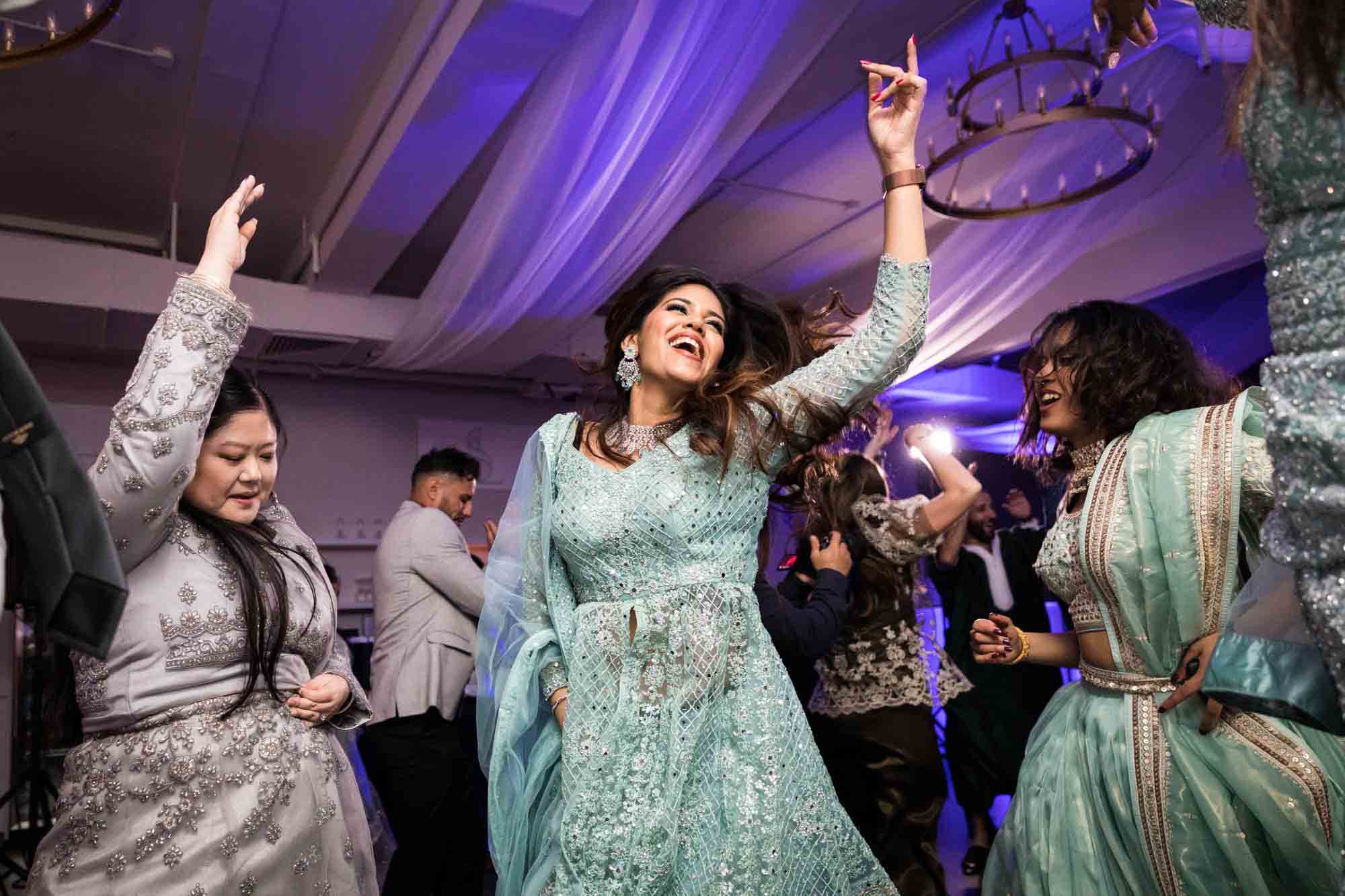 Indian woman in blue sari dancing at a Loft Story wedding
