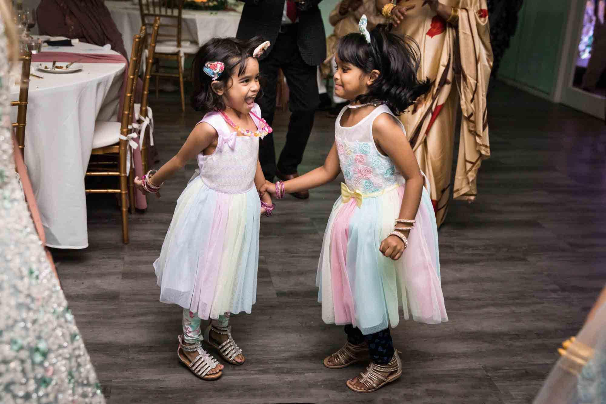 Two little girls in white and pink dresses dancing at a Loft Story wedding
